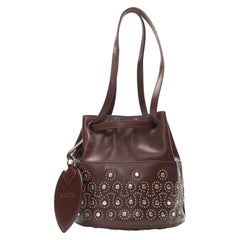 ALAIA - Borsa a secchiello con coulisse a specchio con borchie geometriche in rosso borgogna e argento