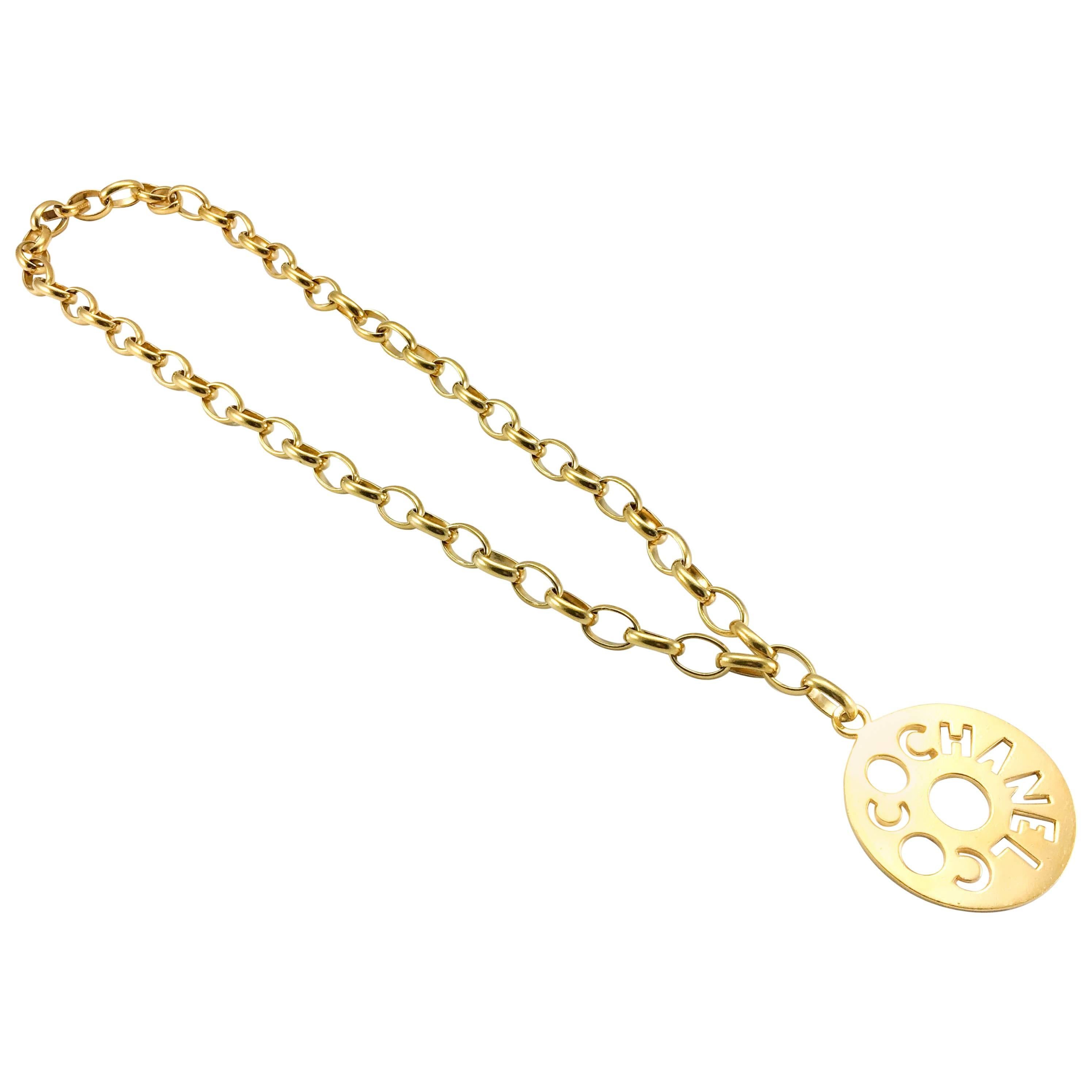 Important Vintage Chanel Gold-Tone Disk Pendant Necklace. This fabulous piece by Chanel dates from the late 1970’s. Made in gilt metal, it features a long and chunky chain with a disk medallion pendant reading ‘Coco Chanel’. This bold 1970’s design