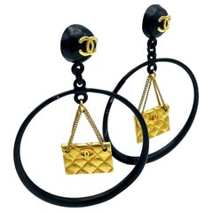 Iconic Chanel black Circle clip-on earring with gold Chanel bag hanging, 1990s