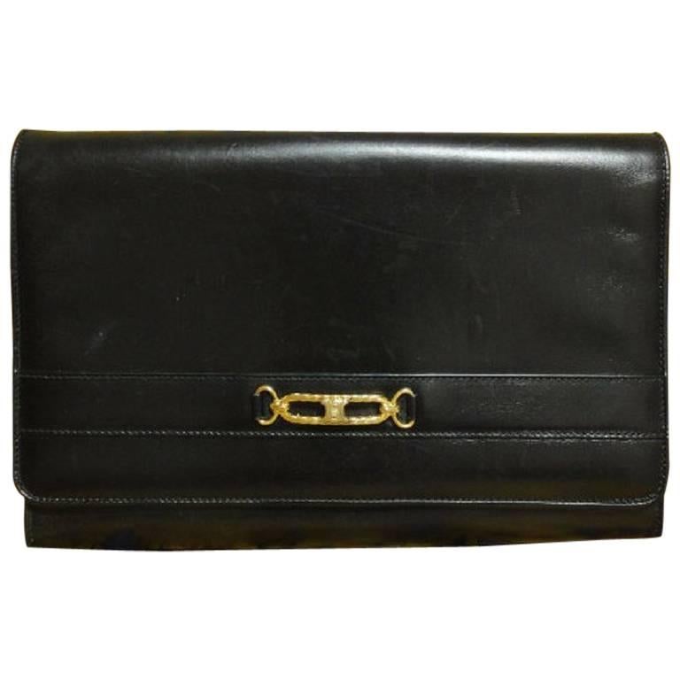 Vintage Celine black calfskin leather clutch bag with iconic golden logo motif. For Sale