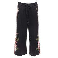 Gucci, joggers a gamba larga con tasca a zip in fettuccia nera e patch floreale