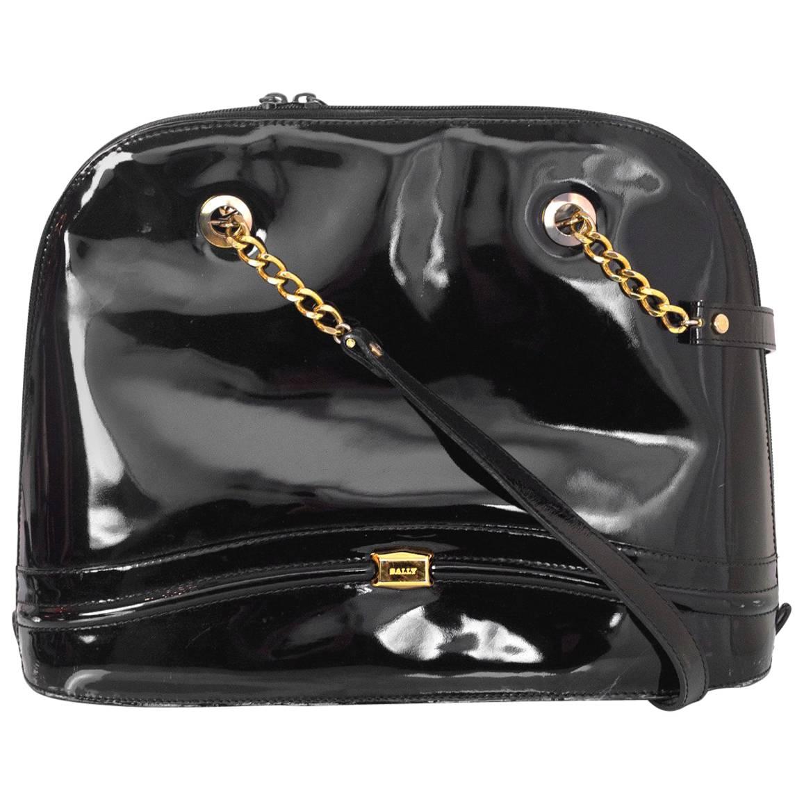 100% Authentic Bally Black Patent Shoulder Bag. Features decorative seaming and metal logo at bottom. Zip top closure with chain and leather shoulder straps. Black leather lining with one interior zip pocket. Very good pre-owned condition with the