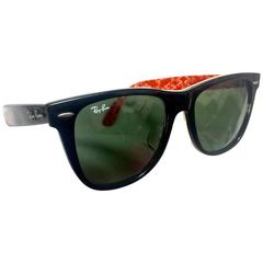 Retro Ray Ban black frame and grey shade sunglasses with red and white logo.