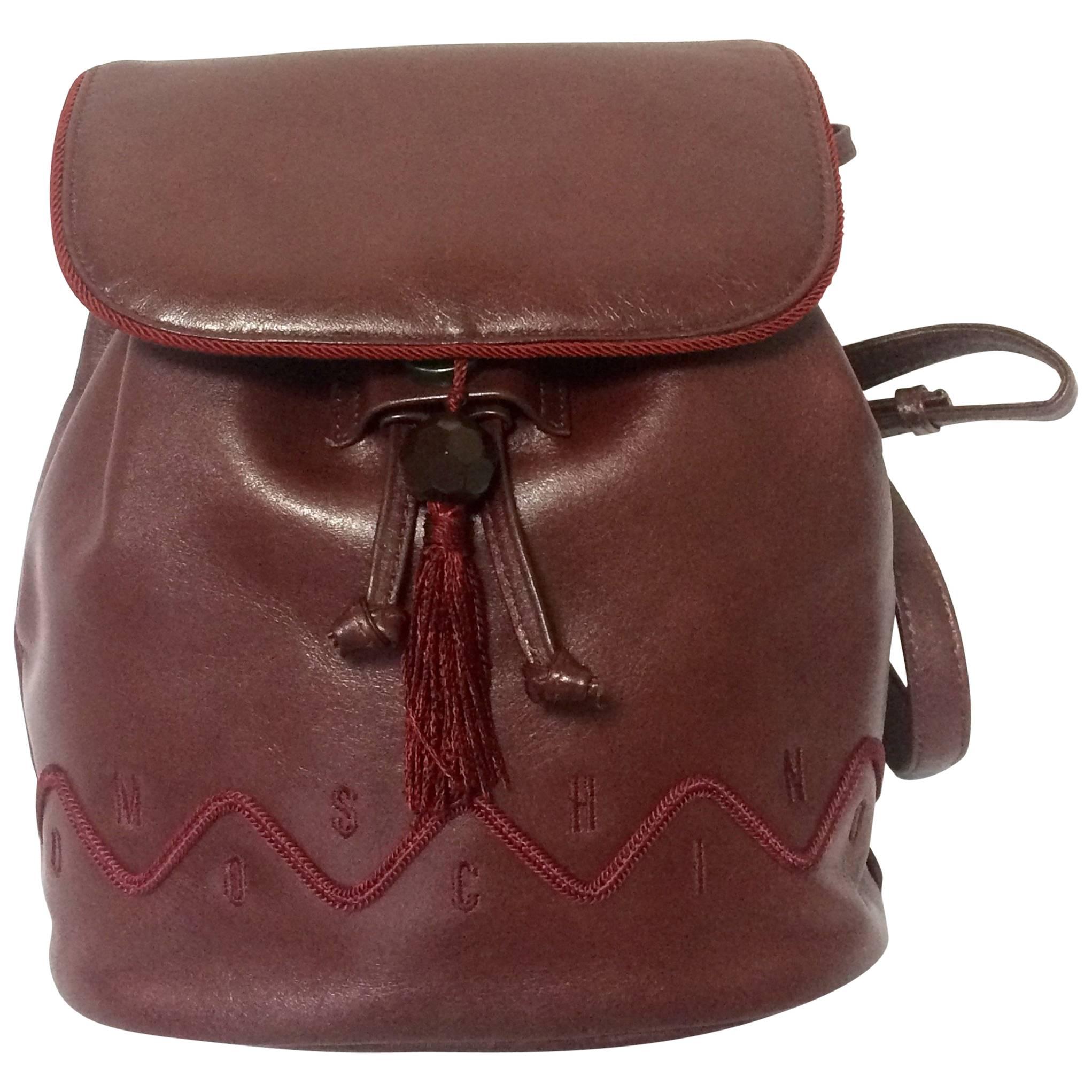Vintage MOSCHINO dark wine leather backpack with tassel and logo embroidery. For Sale