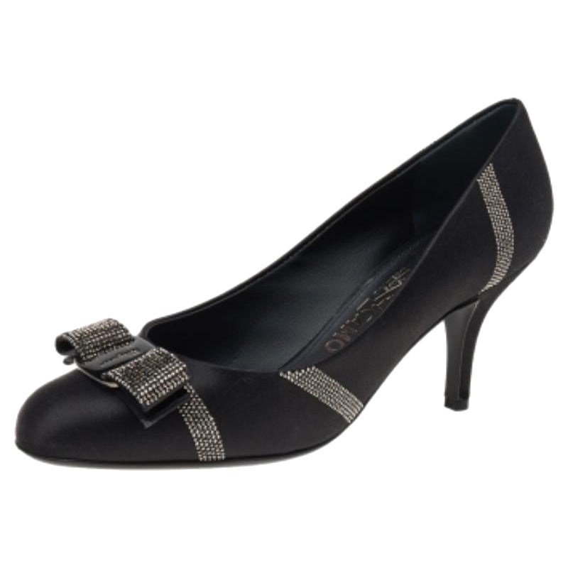 De una de las colecciones más célebres de la Casa, estos zapatos de salón Vara Bow de Salvatore Ferragamo son un diseño que no te puedes perder. Están confeccionados en satén negro y lucen el característico detalle Vara Bow adornado con cristales en