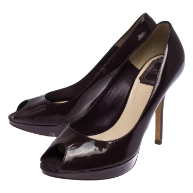 Verleihen Sie Ihrem Look mit diesen Pumps aus Lackleder einen Hauch von Magie. Dieses Paar Dior-Pumps ist mit Peep-Toes, hohen Absätzen und dem Markenlogo auf den Zählern gestaltet. Mit diesem Paar lilafarbener Pumps liegen Sie voll im Trend der