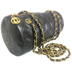 Vintage CHANEL black lamb leather golden chain shoulder bag in round drum shape.