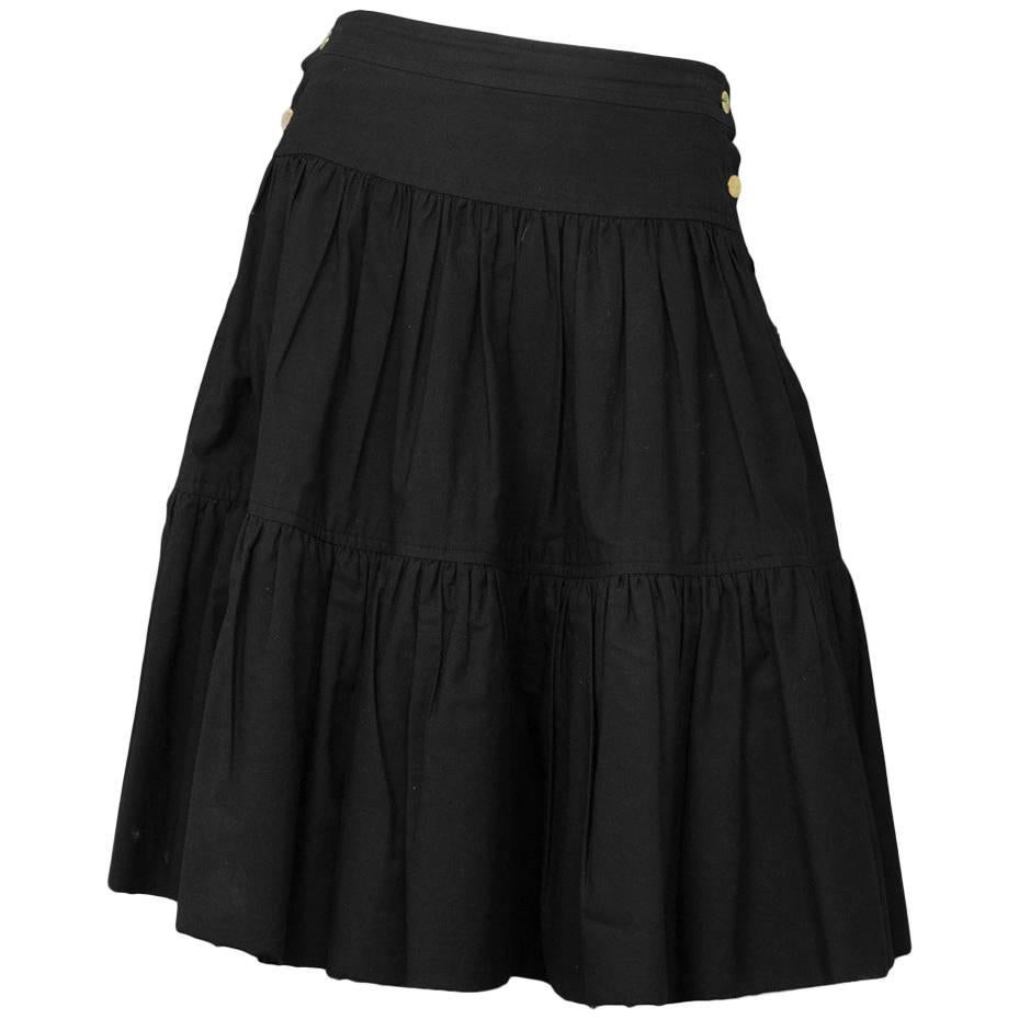 Chanel Black Cotton 2-Tier Skirt 
Features raw hemline and goldtone buttons down both sides

Color: Black
Composition: Not given- believed to be 100% cotton
Lining: Black, cotton-blen
Closure/opening: Double sided button up closure
Exterior Pockets: