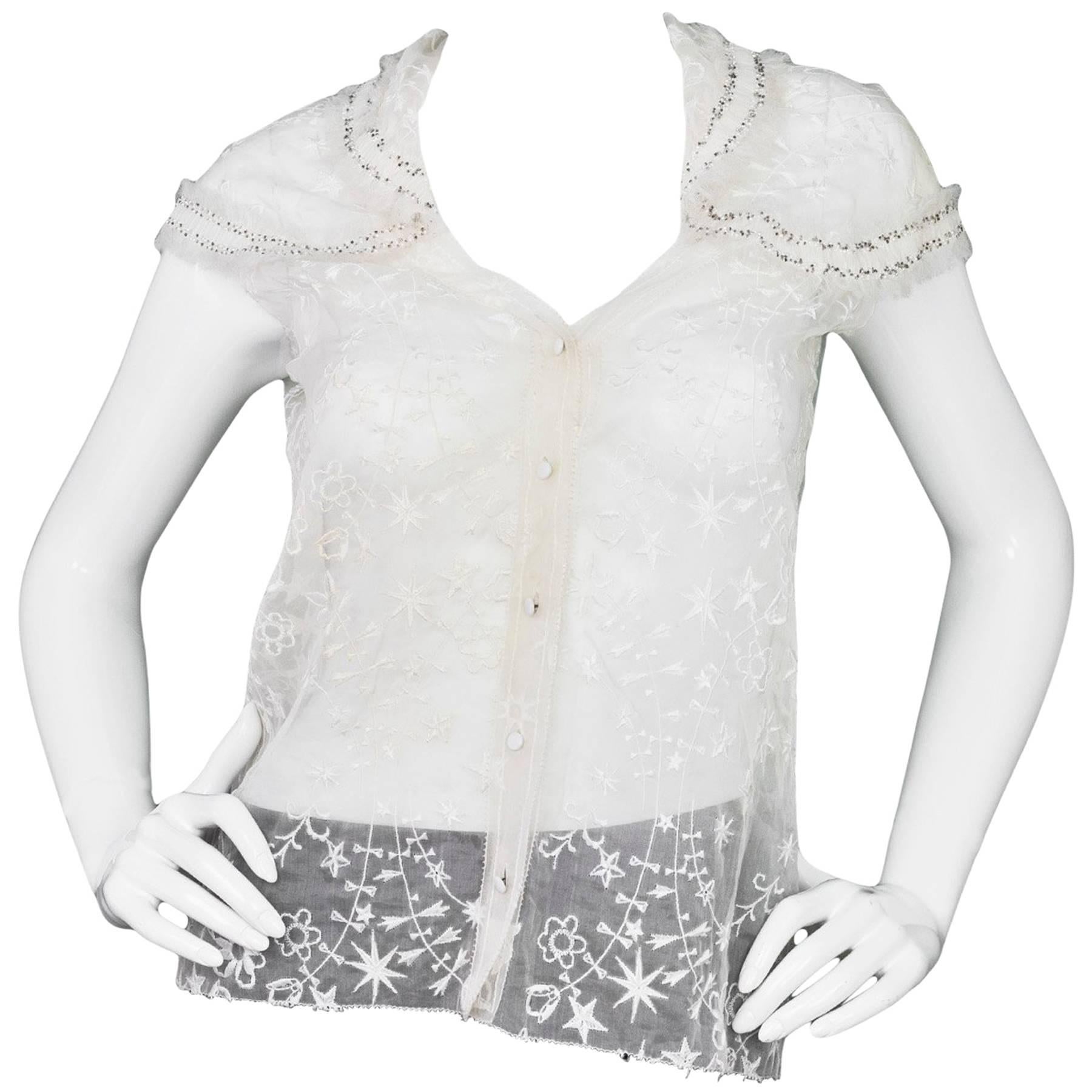 Nina Ricci White Embroidered Silk Cap Sleeve Top
Features beading and fringe throughout neckline and sleeves

Made In: France
Color: White
Composition: 100% silk
Lining: None
Closure/Opening: Button up front
Exterior Pockets: None
Interior Pockets: