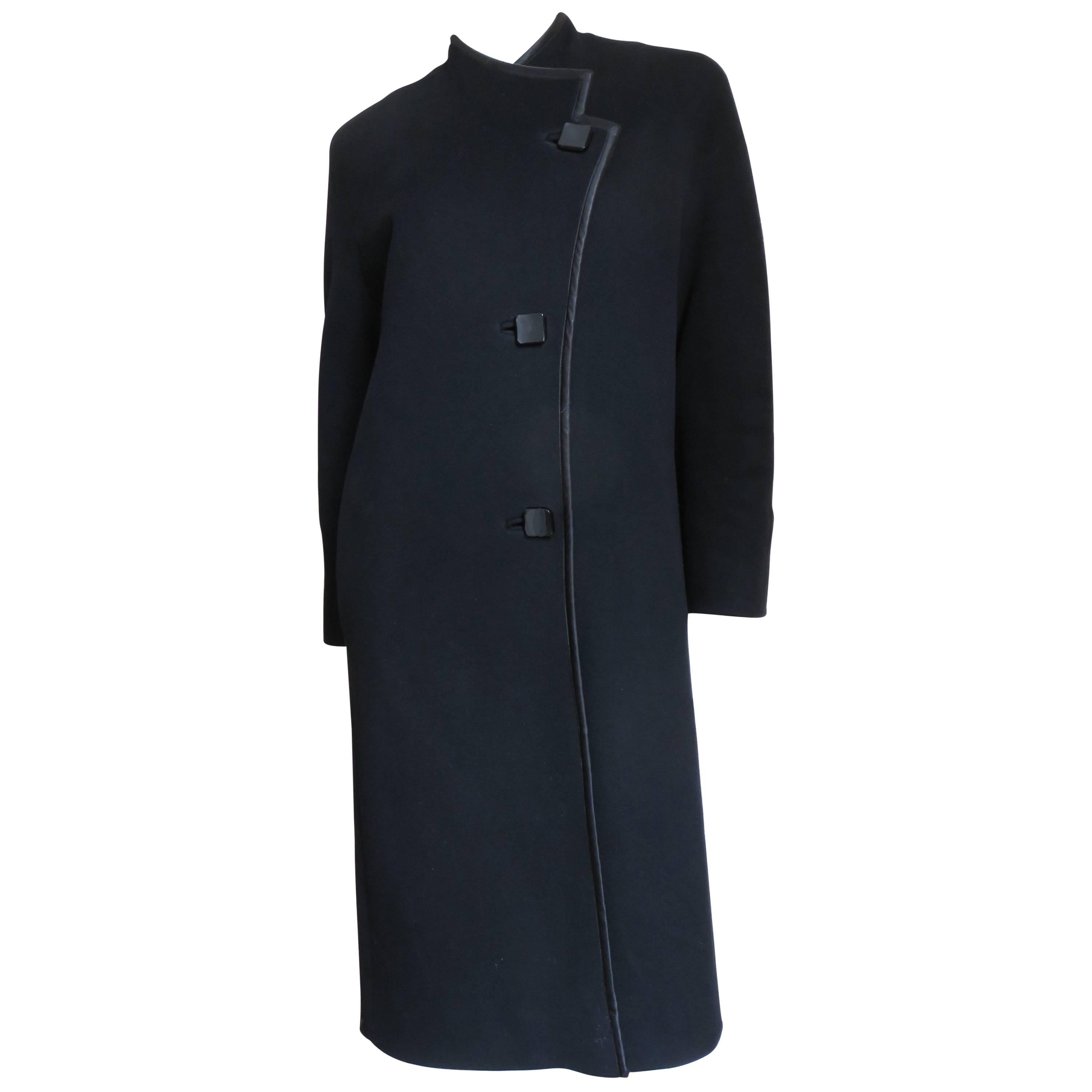 A great black wool coat from Zandra Rhodes.  It has an asymmetric front closing with three square buttons and bound buttonholes.  Cleverly the sleeves and stand up collar are cut in one piece with front and back of the coat creating modest dolman