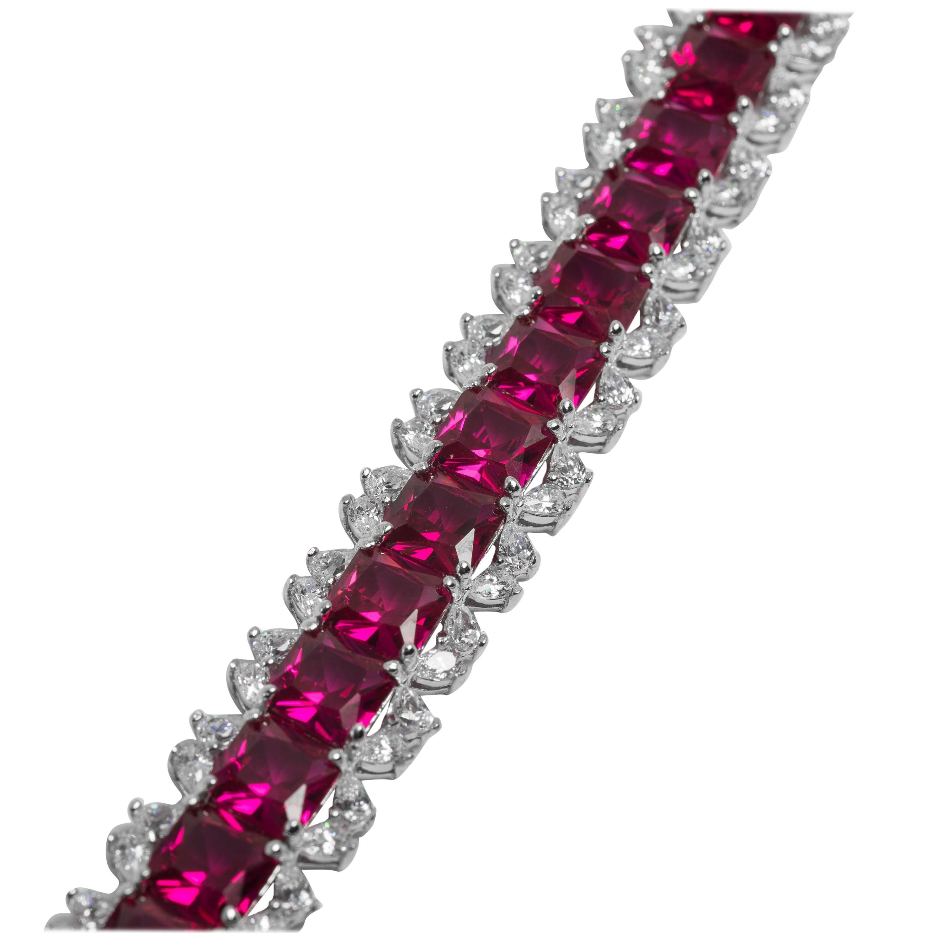 Straight line bracelet of man-made 1 carat Burma rubies edged with cubic zirconia totally flexible secure clasp hand set in rhodium sterling seven inches long by half inch wide.
