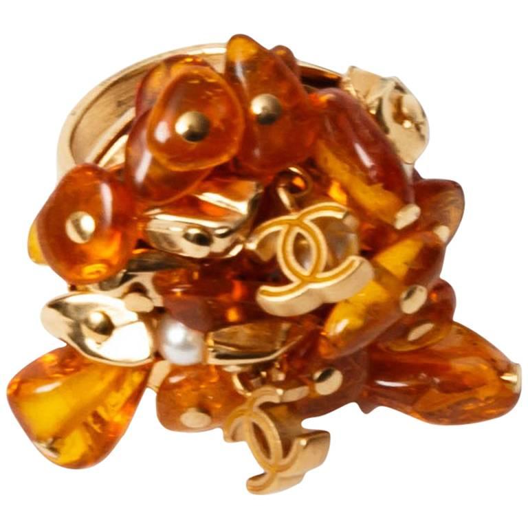 Very cool Chanel ring with individual amber resin pieces and interlocking Chanel logo double CCs on an adjustable gold metal base.
