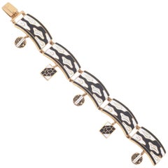 Black and white enamel and gilt panel bracelet with charms, 1950s