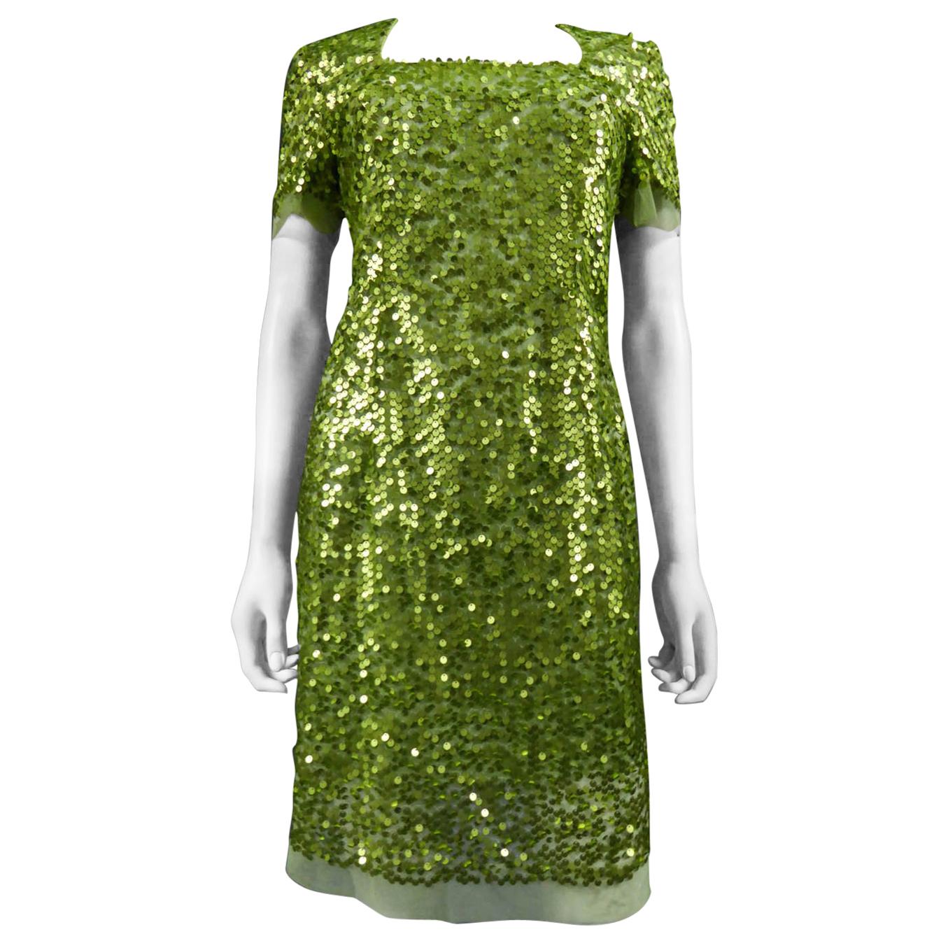 Um 1990
Frankreich

Kurzes Kleid aus grünem Tüll, bestickt mit schillerndem grünem Glitter. Der quadratische Kragen ist eng anliegend und wird am Rücken mit einem Reißverschluss geschlossen. Innenfutter aus grünem Kunststoff. Kein Etikett, sondern