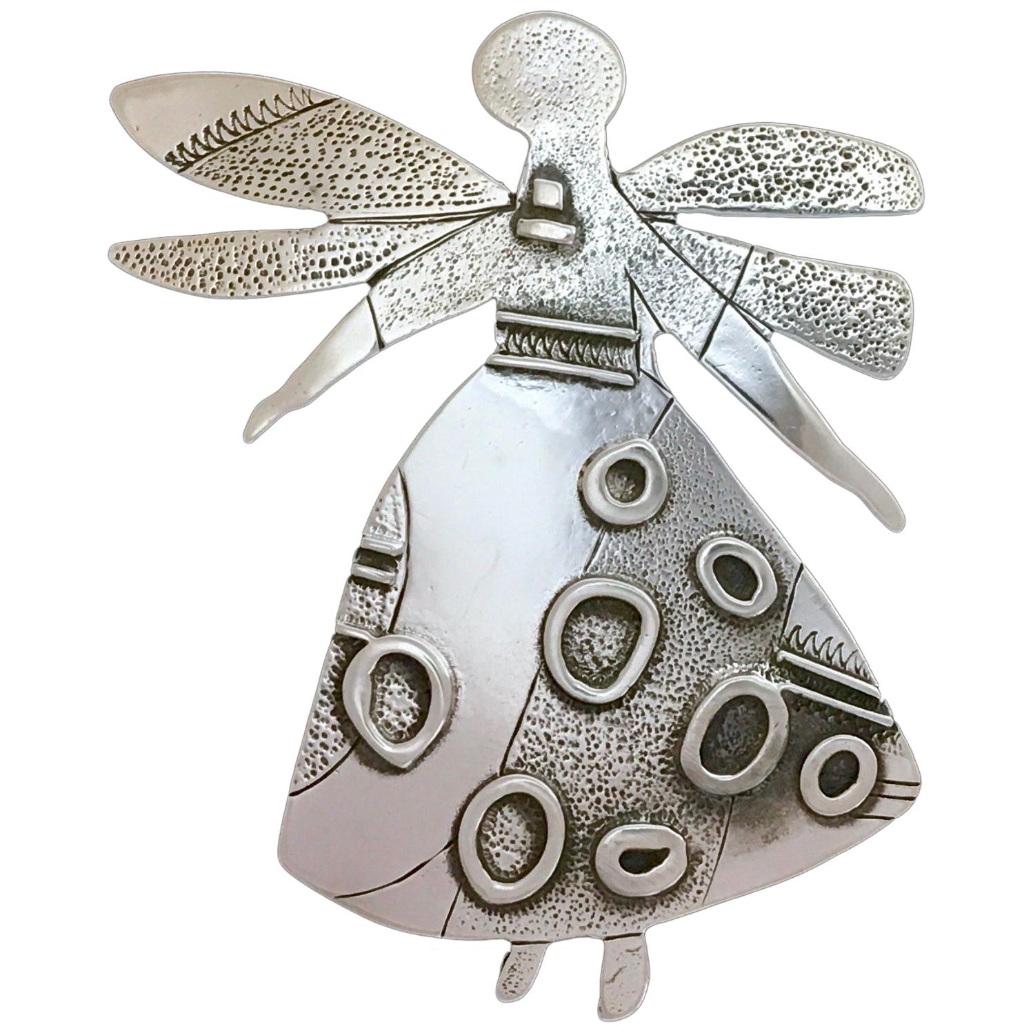 Salt Water Girl, Melanie Yazzie enhancer, pendant, sterling silver,  Navajo 

Melanie A. Yazzie (Navajo-Diné) is a highly regarded multimedia artist known for her printmaking, paintings, sculpture, and jewelry designs.

She has exhibited, lectured,