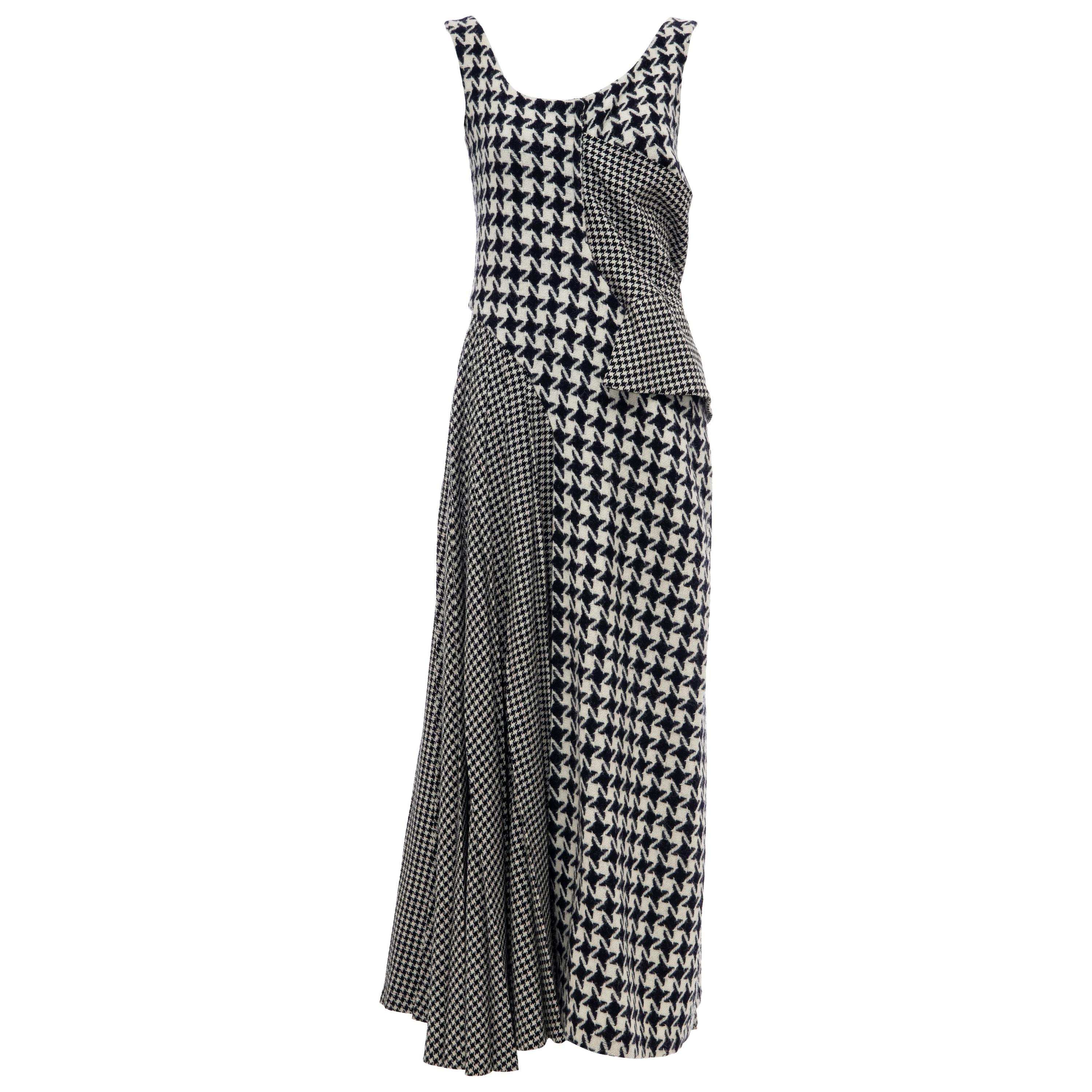 Yohji Yamamoto, Fall 2003 Runway wool sleeveless scoop neck dress featuring various sizes of houndstooth in both navy and black color ways, a side peplum and draped pleating at the right hip and back with concealed snap closures at back.

 Designer