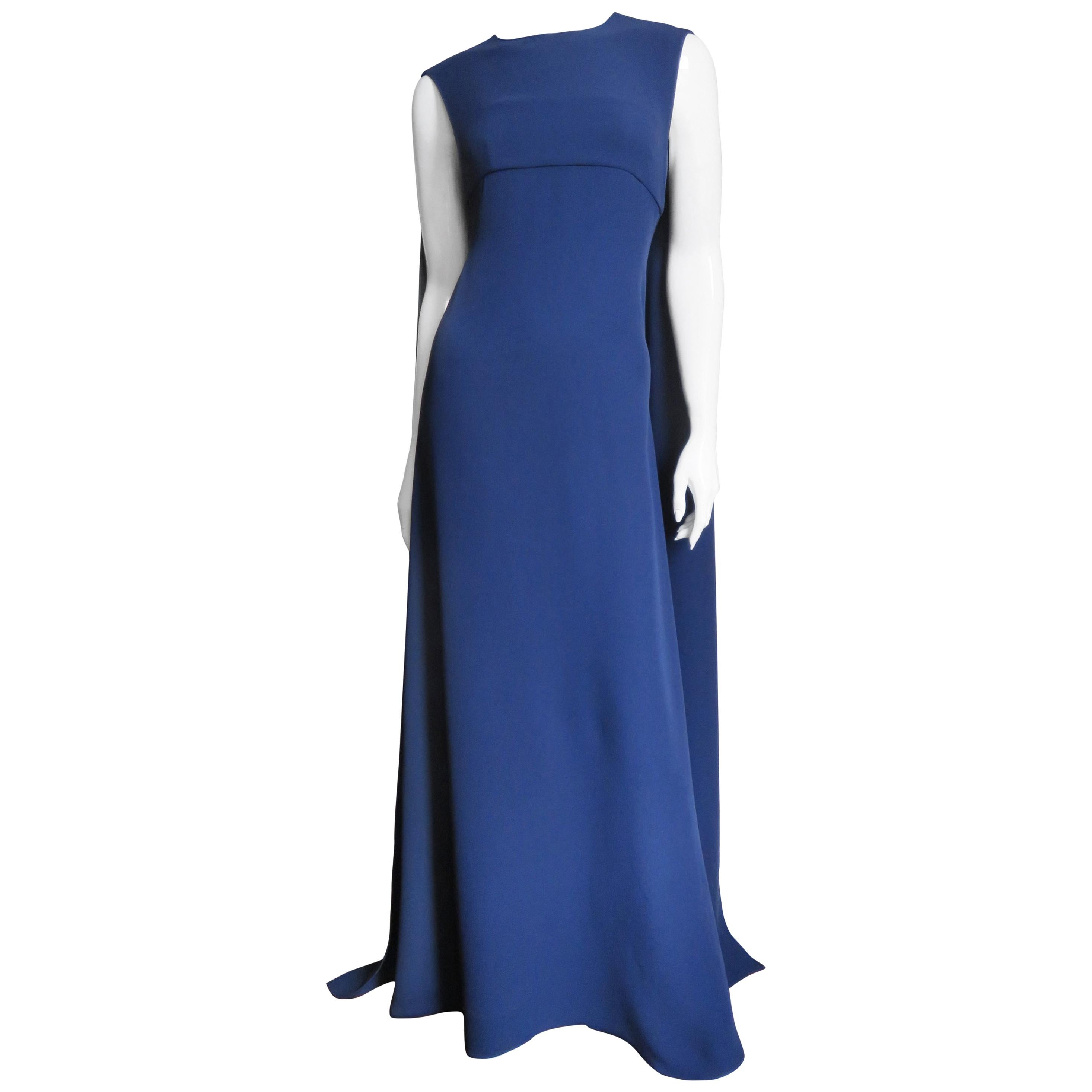 A fabulous navy blue silk cape dress from Valentino.  It is sleeveless with a panel forming a cape draping over the shoulders in the back closing at the neck with a keyhole and self covered button and loop above it. The dress is fitted with light