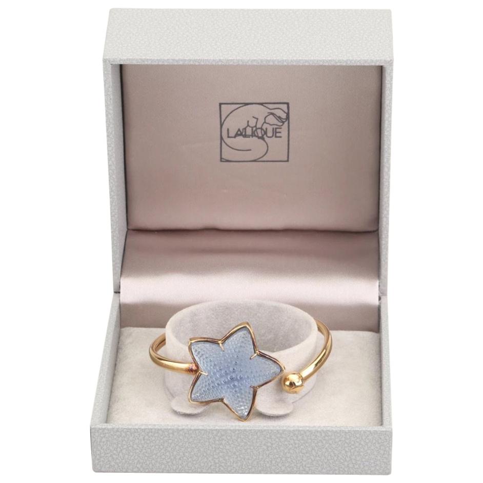 Modernist Inspired by the magic of the ocean depths, evokes nature, a theme dear to Maison Lalique.
The Raised Blue Textured Starfish of satin & polished crystal subtly captures the light. The French cuff is gold plate over sterling in a Lalique