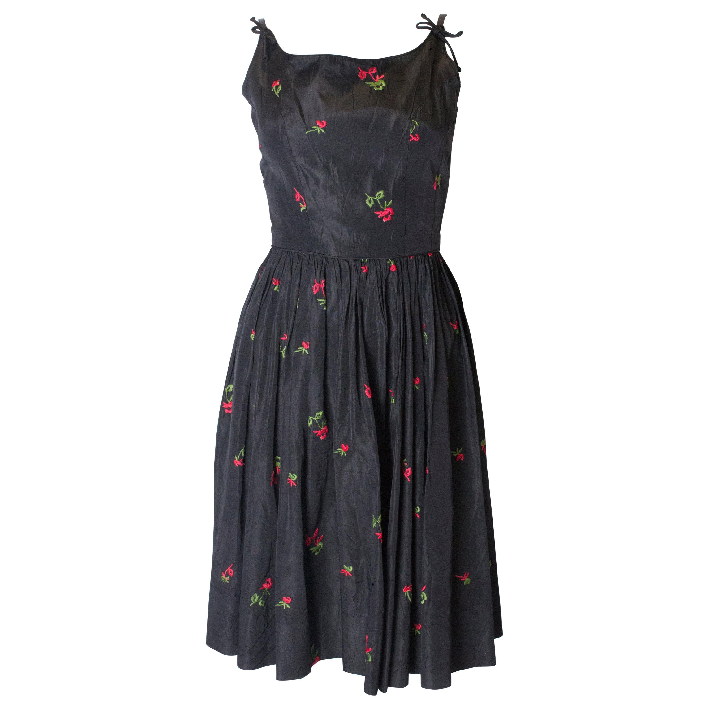 A vintage 1950s black cinch swing dress with embroidered flowers 