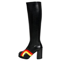 Bottes noires vintage hauteur genou avec plateformes et rayures jaune et rouge, style glamour et rock, années 1970