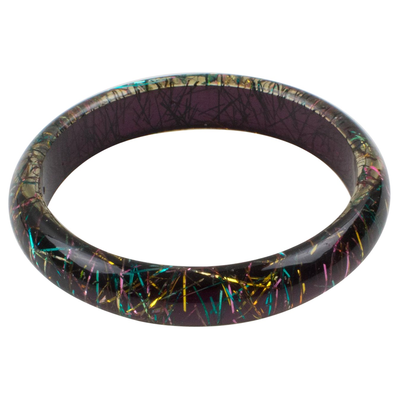 This lovely Lucite bracelet bangle has a domed shape and is comprised of clear Lucite, which is injected with metallic thread inclusions in multicolor tones with a deep purple background. The metallic threads sparkle like those of Christmas tinsels.