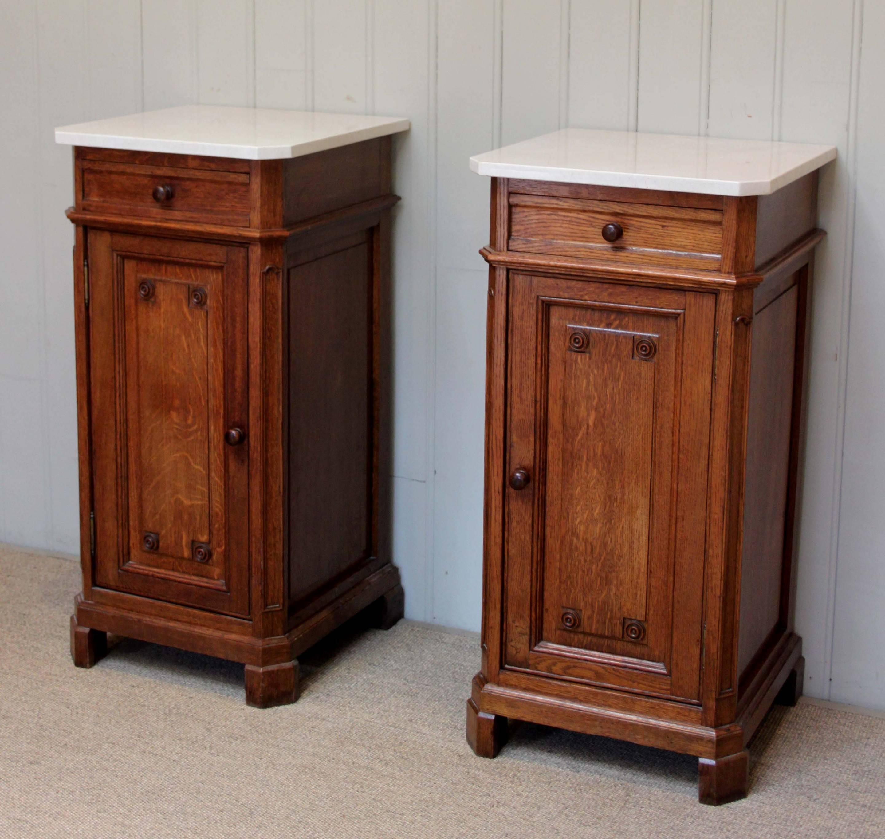 Pair of French oak bedside cabinets having marble tops with a single drawer above a long cupboard base with carved detailing to the doors raised on bracket feet