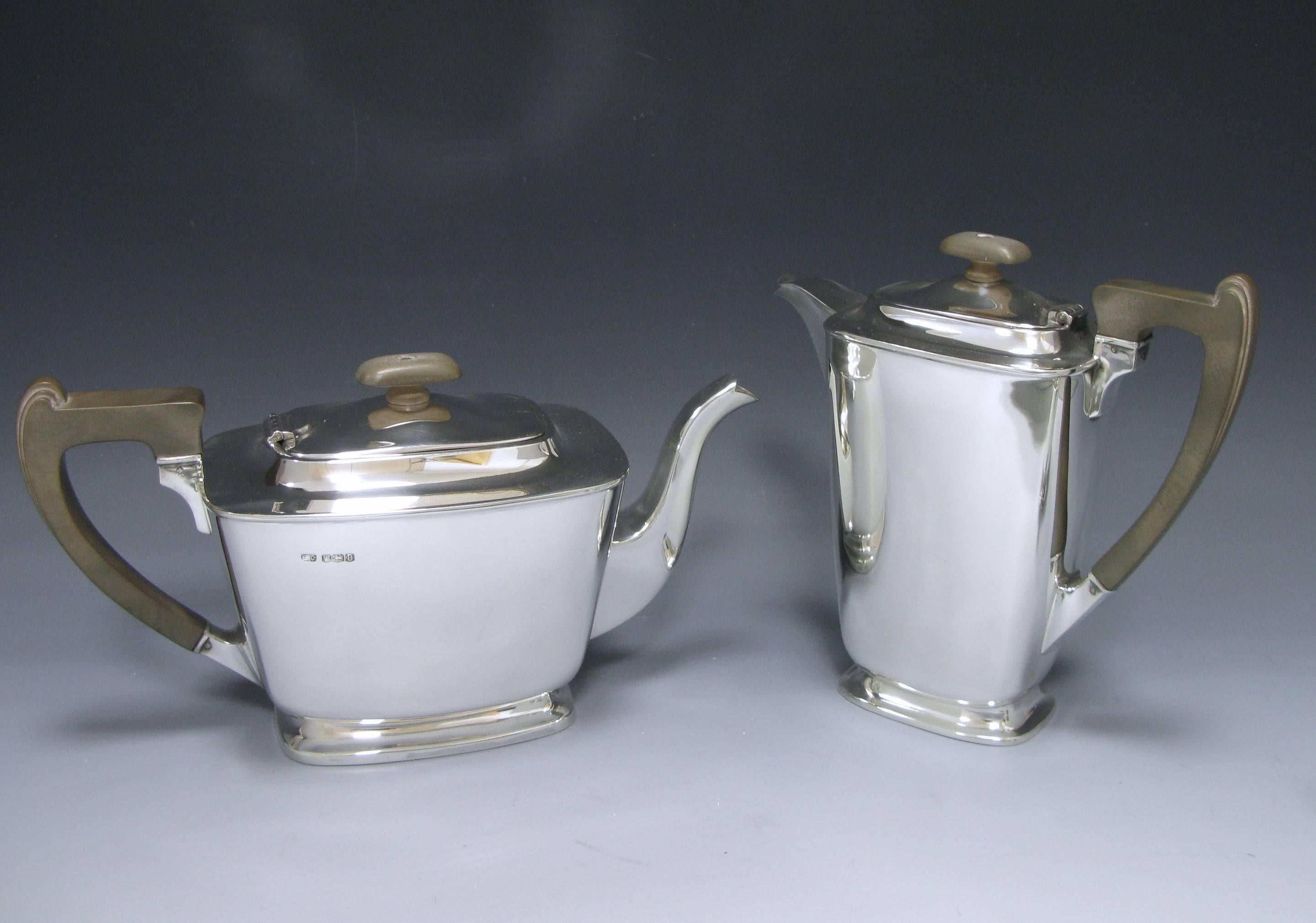 A four-piece sterling silver tea and coffee service of plain elegant form, the tea and coffee pots have caves wooden handles and finials height of coffee pot 6.5 inches, 16.5 cm, height of tea pot 4.75 inches 12 cm, cream jug 3.50 inches, 9 cm sugar