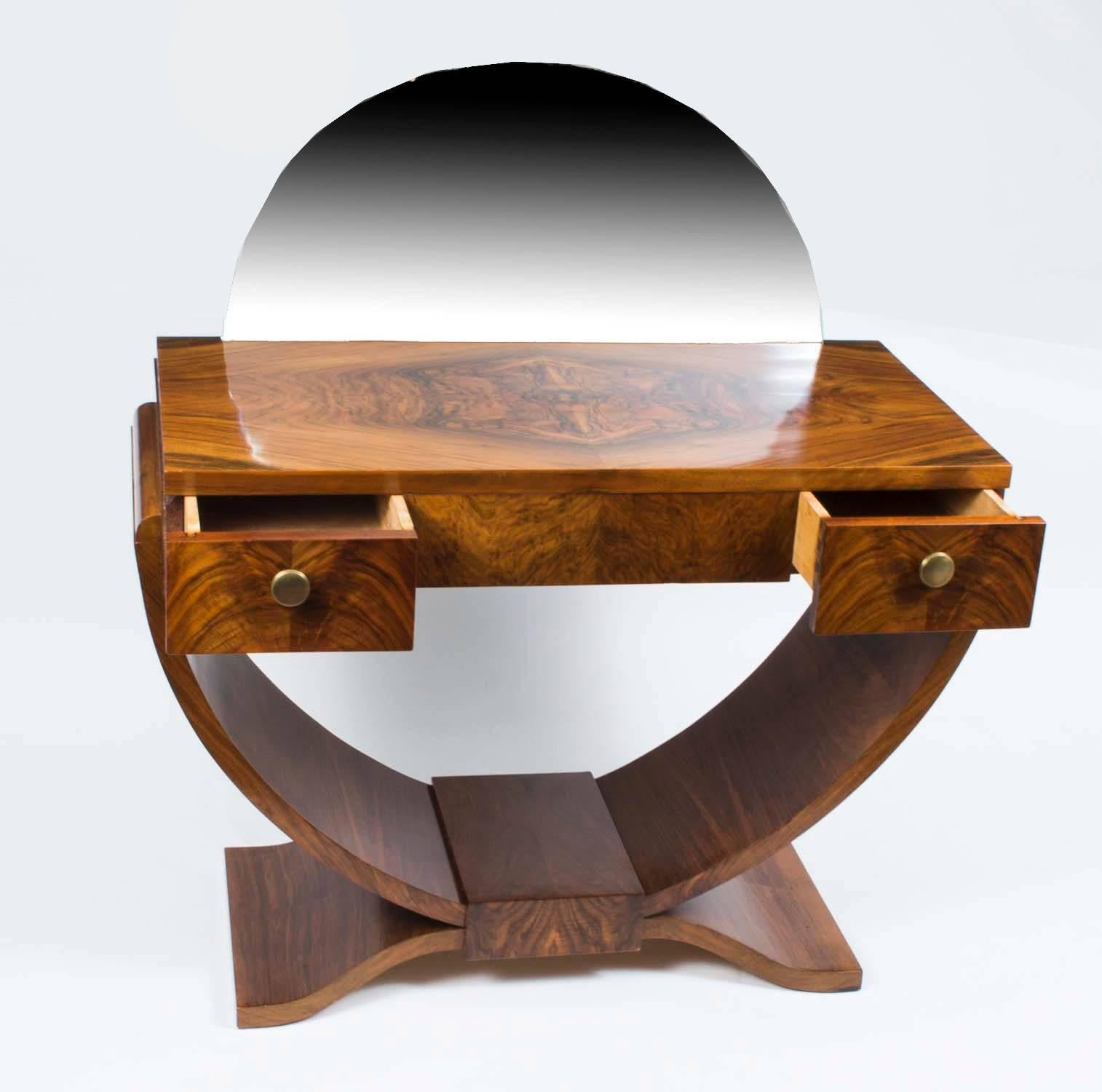 This beautiful antique French Art Deco burr walnut dressing table, circa 1925 in date, features classic minimalist Art Deco contours. 

The grain of the burr walnut is butterflied on the top forming a beautiful veneer crest. The front features two