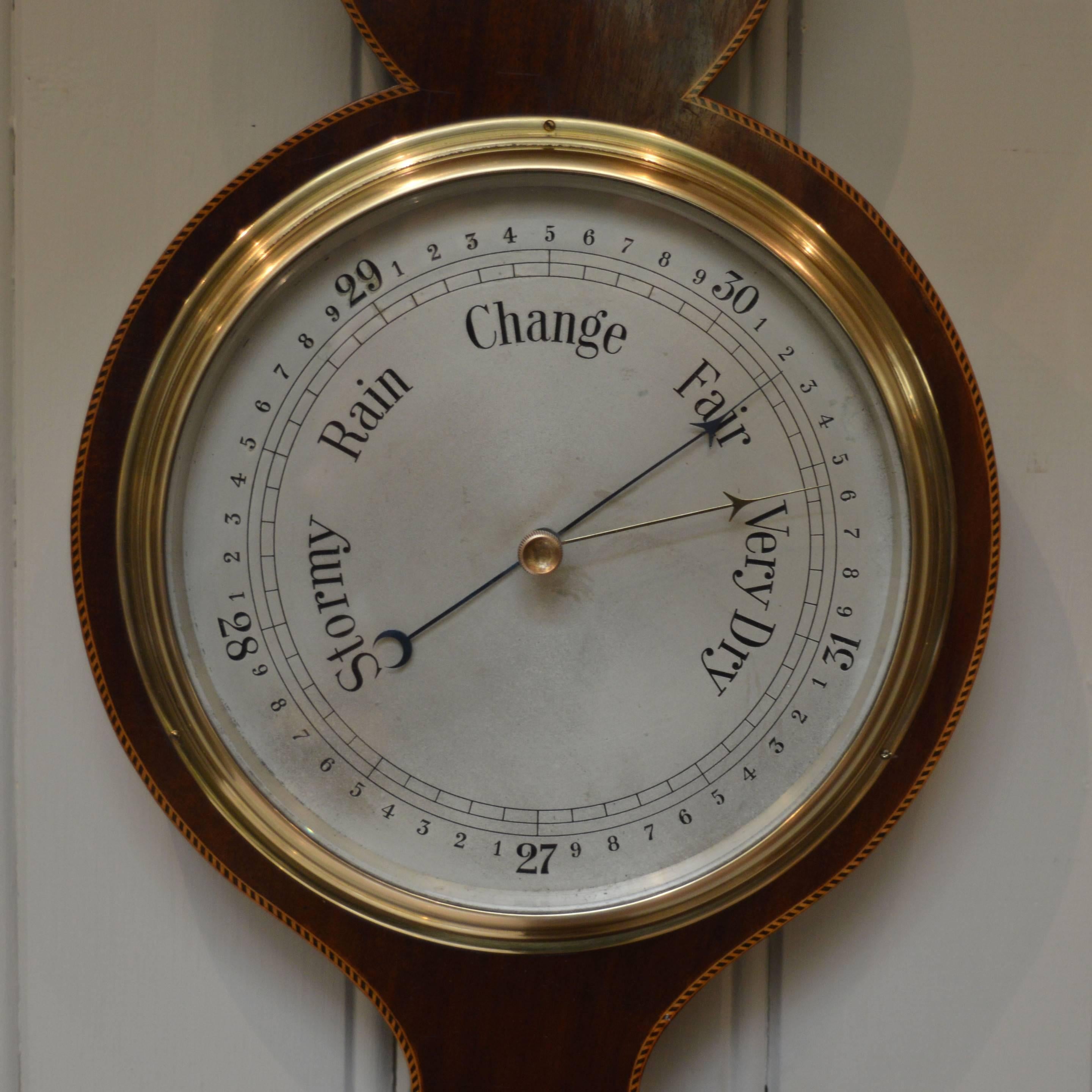 A solid mahogany banjo barometer, having a case with a break arch pediment with a brass finial and inlaid with boxwood inlays. It has an aneroid movement , with an alcohol thermometer. This barometer does not contain mercury so it can easily be