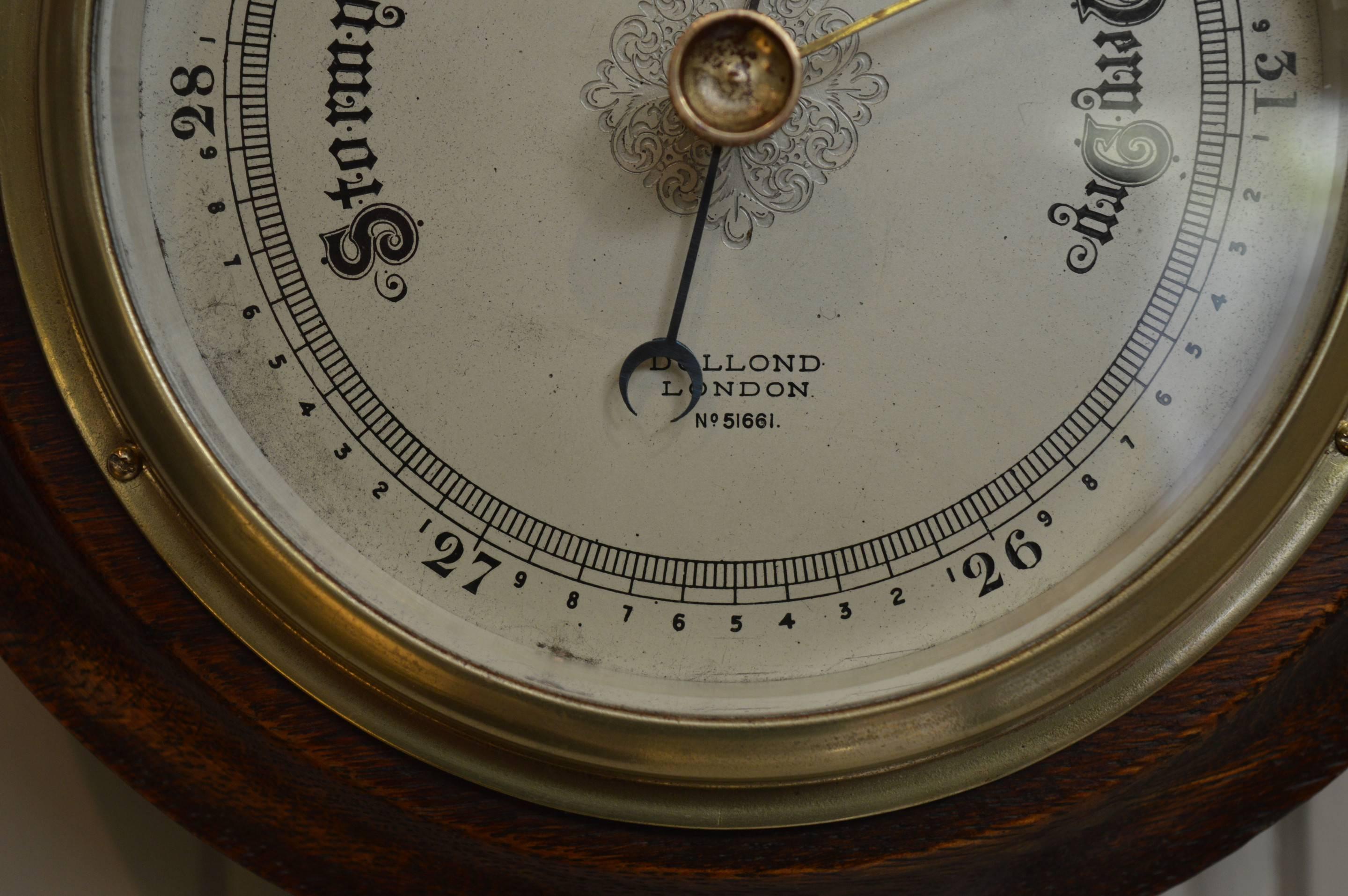 A solid oak case barometer made by Dolland of London and is numbered 51661. It has a stepped turned case, and an engraved, silvered dial. This can be transported easily as it does not contain mercury.