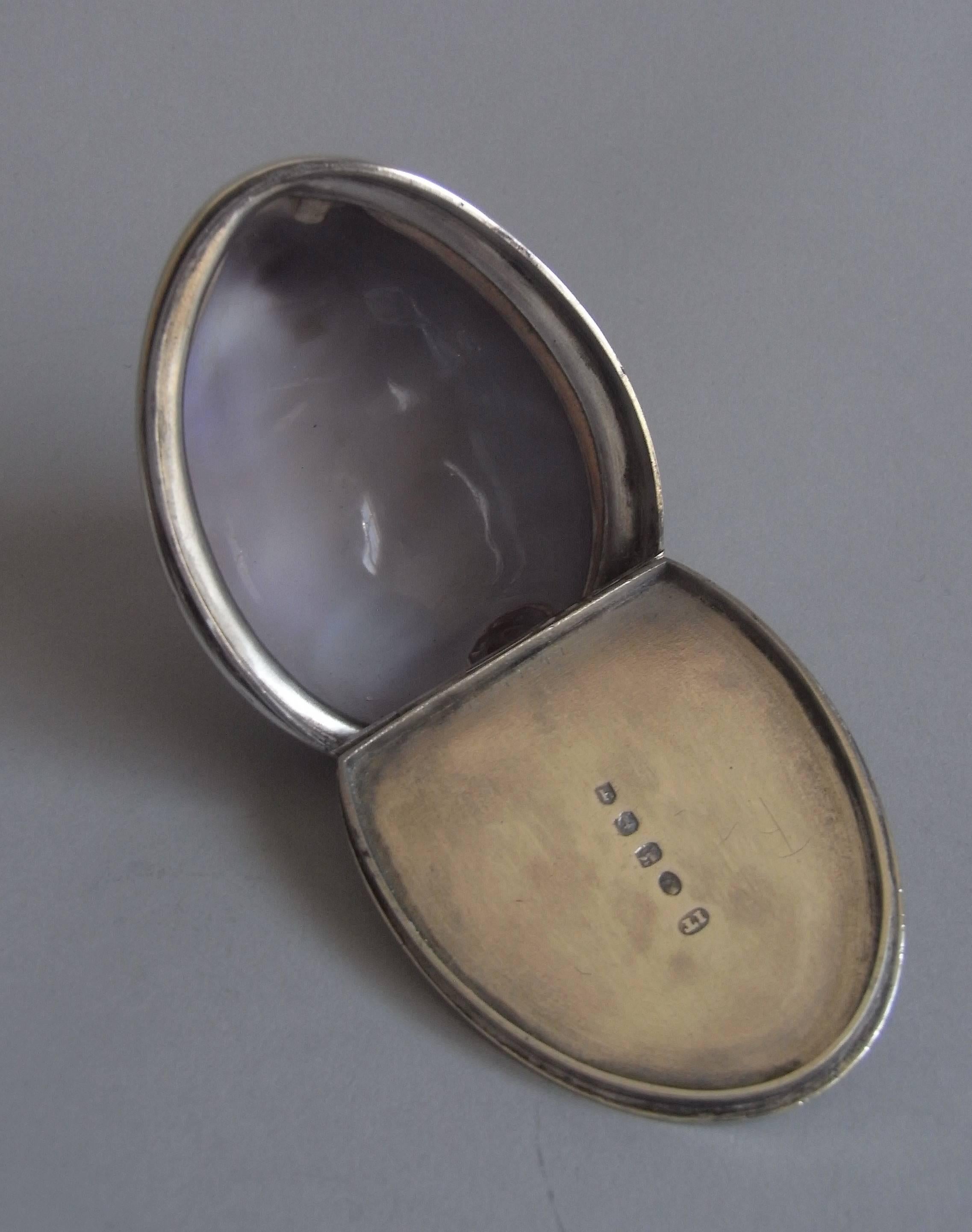 The beautifully shaded Cowrie shell displays plain silver mounts and the hinged cover is engraved with an outer Greek key border, concealed hinge, and central vacant shield shaped cartouche. This piece is in excellent condition and is very well