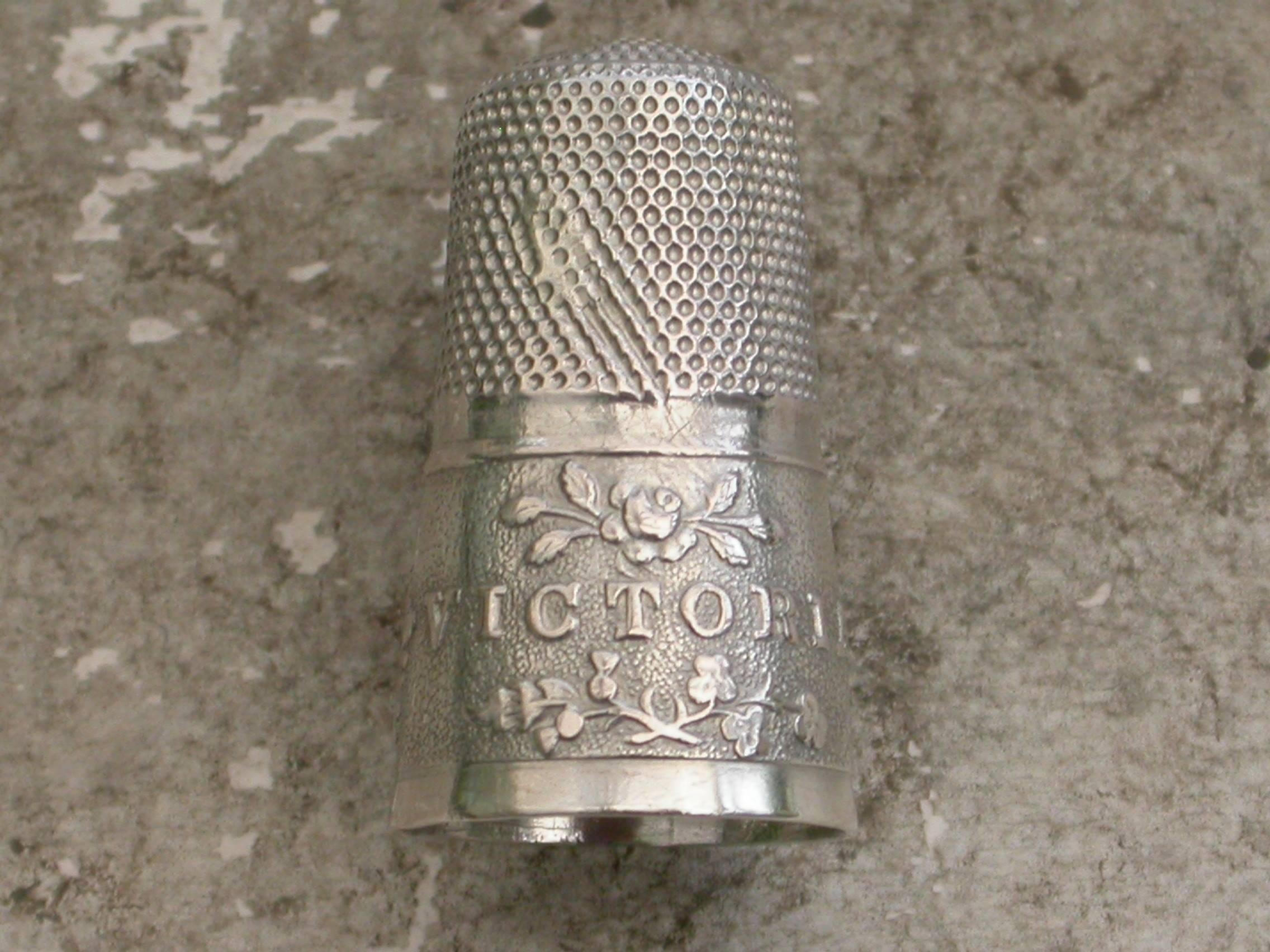 A rare Victorian commemorative silver thimble embossed on the wide band with a bust of Queen Victoria(young head), a vacant shield and the word 'VICTORIA' between the flowers of the union (rose, thistle and shamrock).

Made to commemorate the