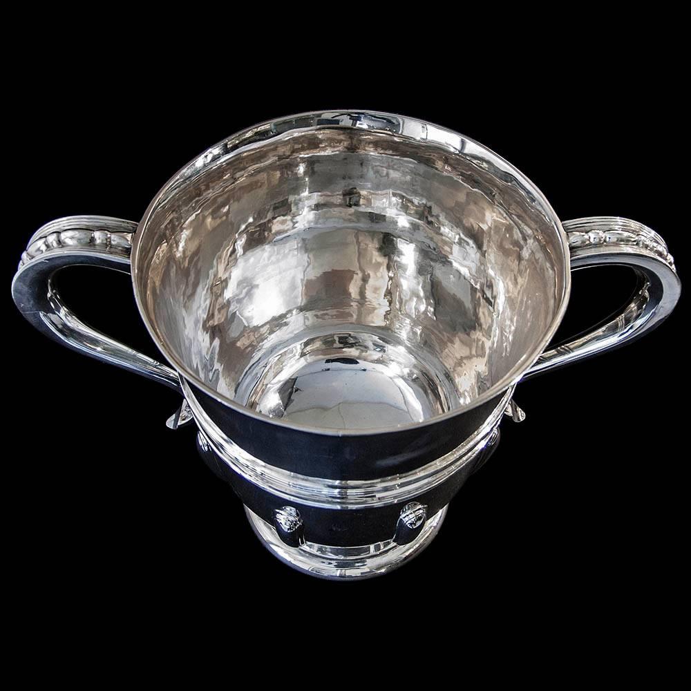 An Edwardian sterling silver two handled cup on a circular foot the plain body having applied strap-work and thread decoration.