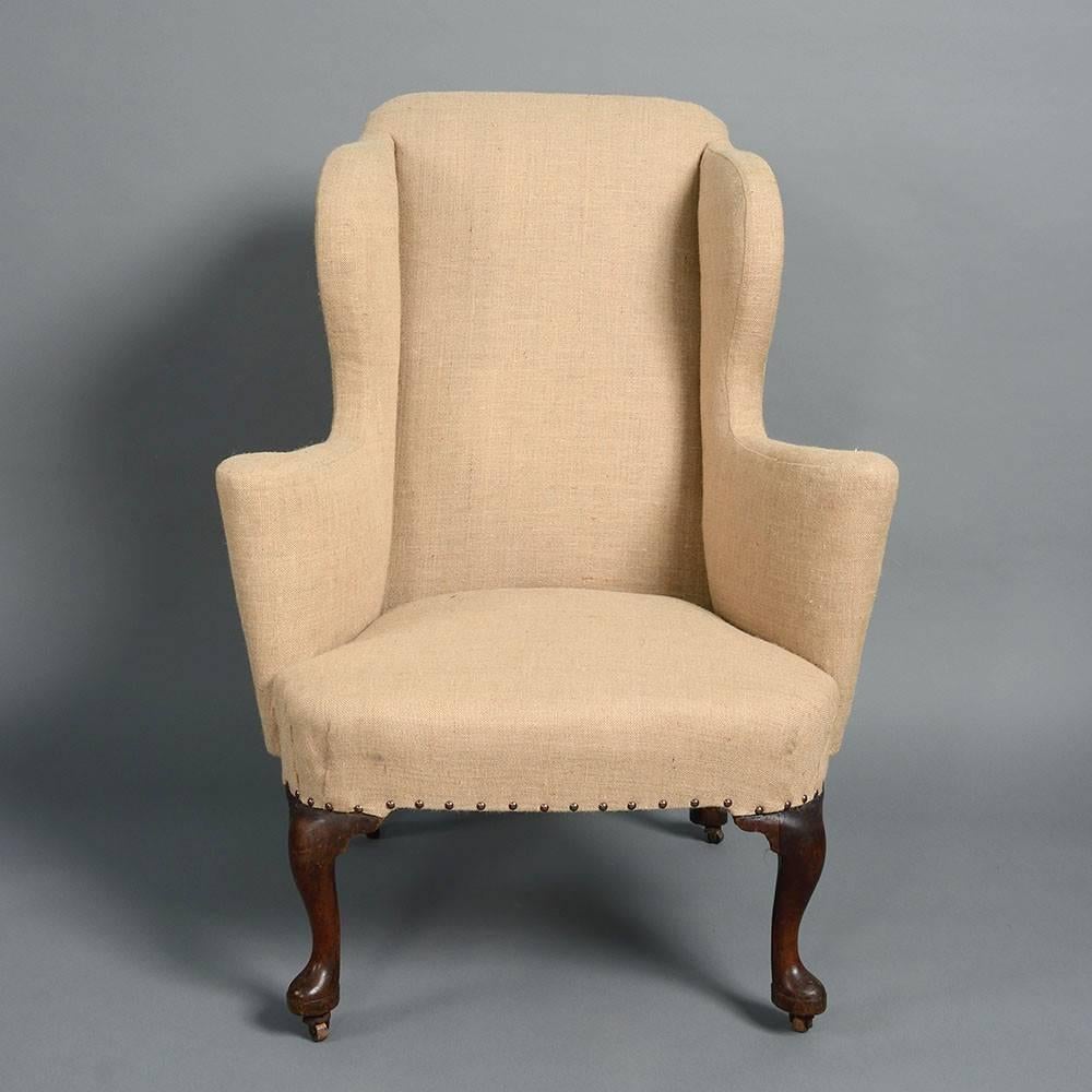 A fine George I Period wing armchair, the shaped seat frame with scrolling armrests and all supported upon generously carved cabriole legs with pad feet. 

This type of armchair can be traced back to late 17th century seat furniture, specifically