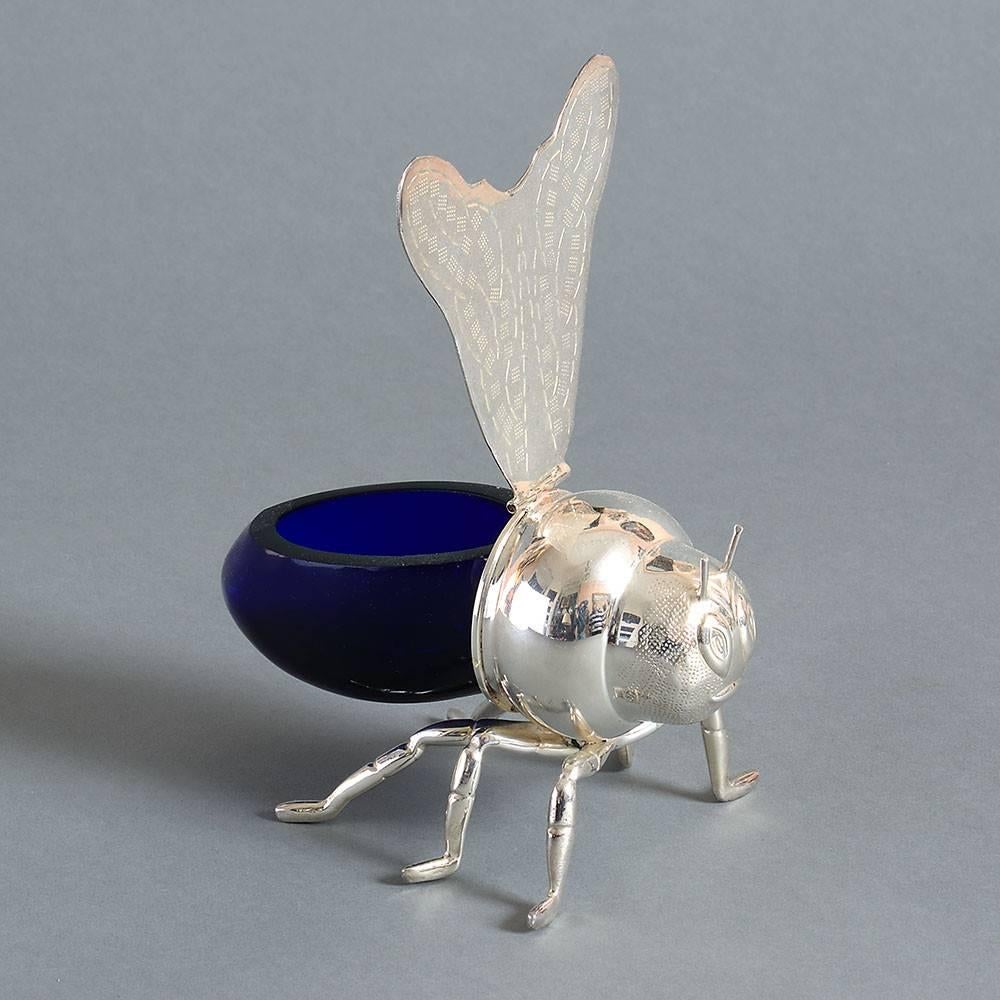 A 20th century silver plated novelty honey pot in the form of a bee, the wings lifting to reveal a hollow Bristol blue glass abdomen.