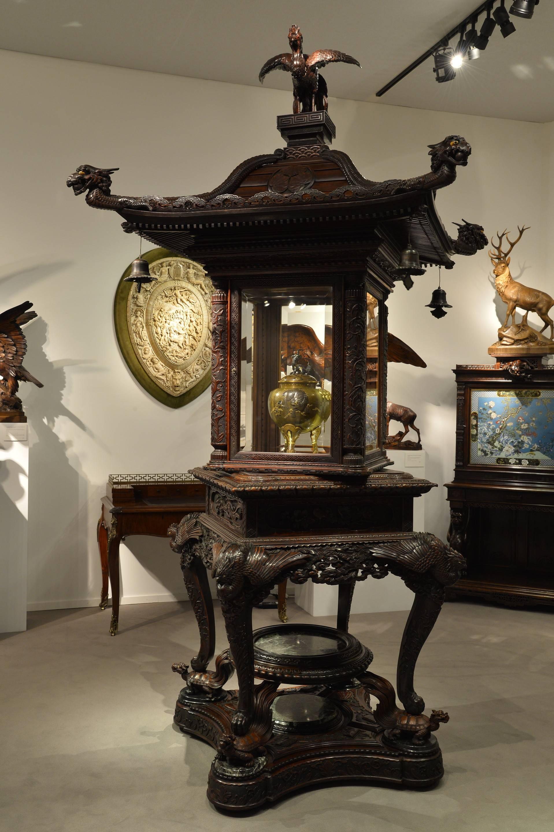 The square central section is glazed, mirrored and rotates, with additional inner frames, all above a frieze with a disguised drawer, surmounted by a pagoda roof with upswept eaves, pendant bronze bells, Aoi mon and serpentine dragons, the finial