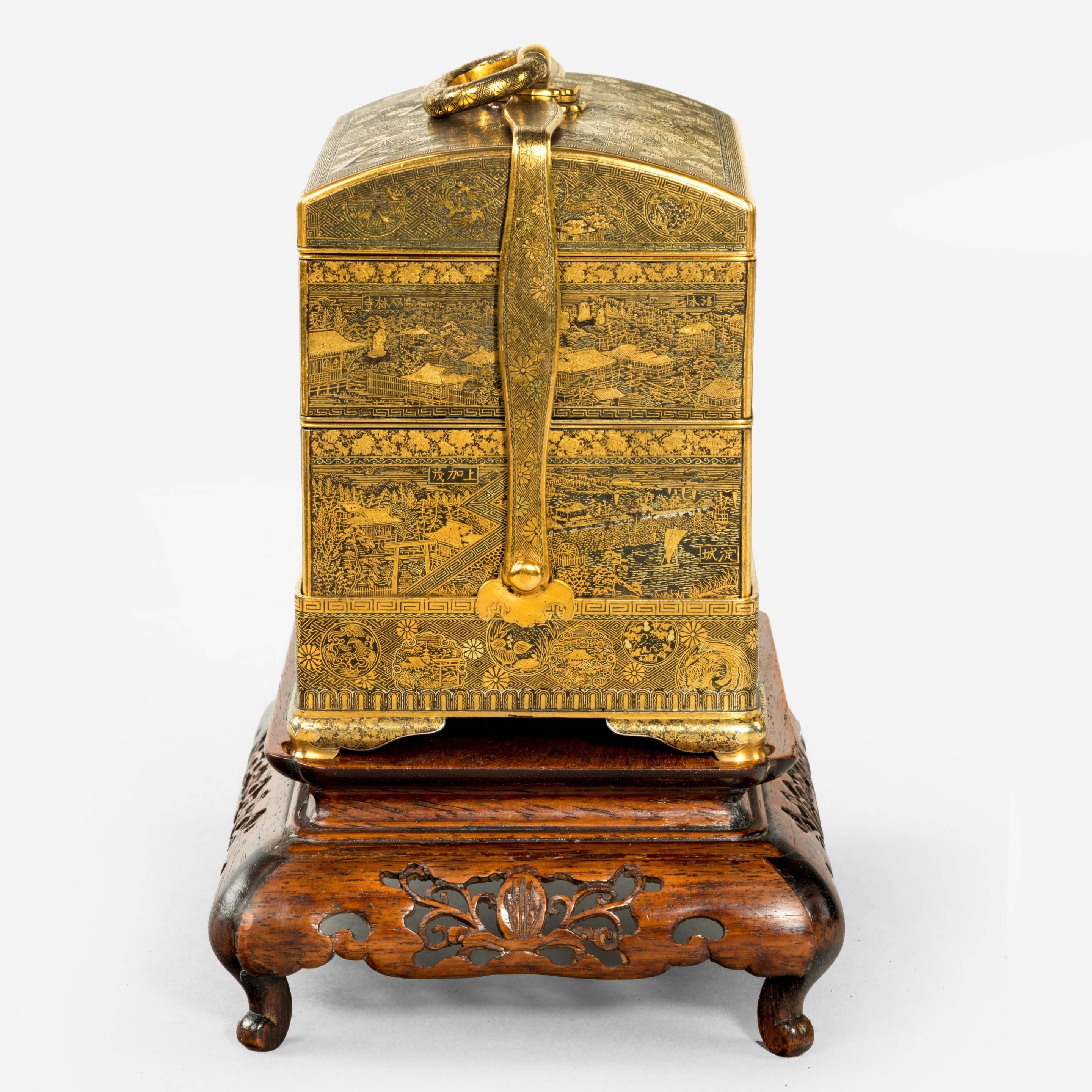 A superb and rare gold inlaid iron jubako (lunch box) by Komai of Kyoto 
Of typical form with three stacking trays secured by a hinged arm which locks into an oval carrying handle, the whole intricately decorated with profuse inlays of various