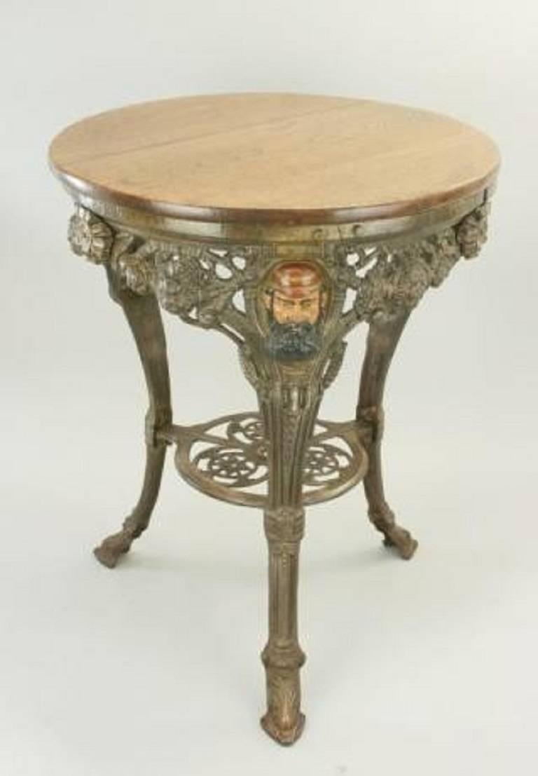 A very good quality Victorian cast iron pub table. The round tripod table has an oak top and three scroll shaped legs. Each leg has a painted image of W.G. Grace\'s face cast in relief with initial W.G. above. Cast into the frame work are also