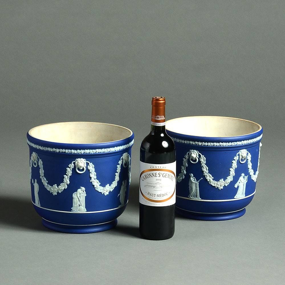 A Pair of late 19th century Jasperware jardinieres with white biscuit Neoclassical decoration of lion masks, swags and figures upon a rich blue ground. 

Both stamped Wedgwood. 
