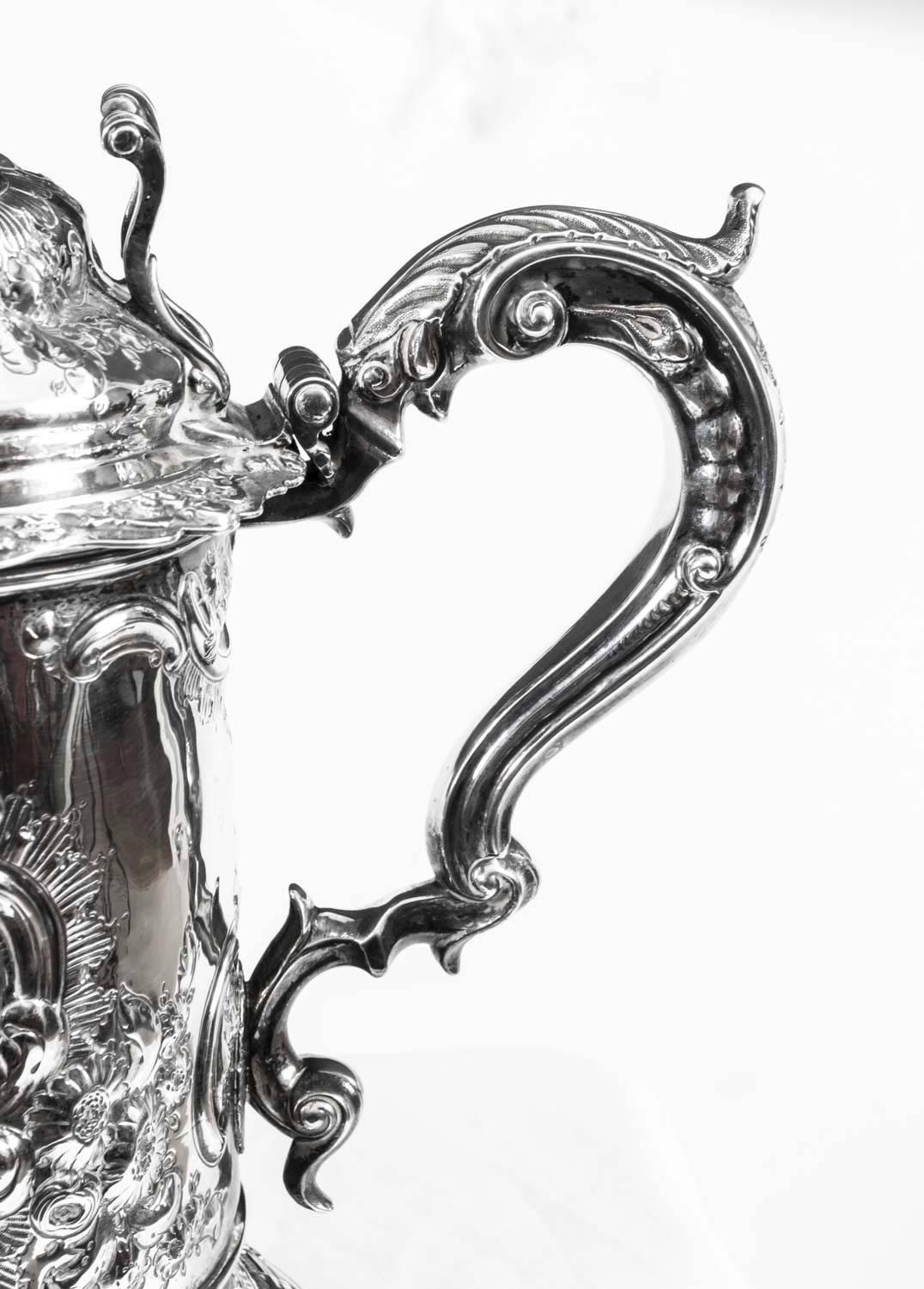 This is a wonderful huge antique English George III sterling silver tankard with spout, which bears hallmarks for London 1810 and the makers mark of Joseph Smith. 

It has wonderful embossed decoration, the work of a master silversmith, and has an