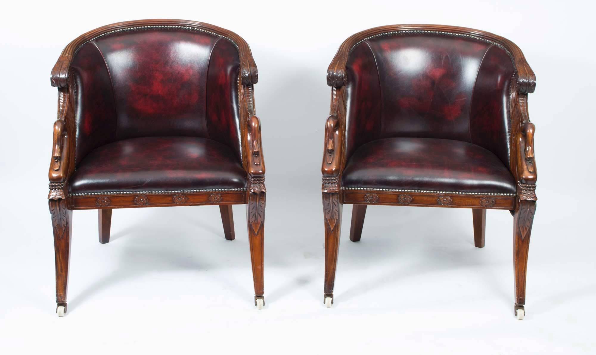 This is a beautiful pair of carved solid mahogany tub shaped armchairs in the fabulous French Empire style and dating from the first half of the 20th Century. 

They have beautiful carved swan arm supports and acanthus decorated sabre front legs