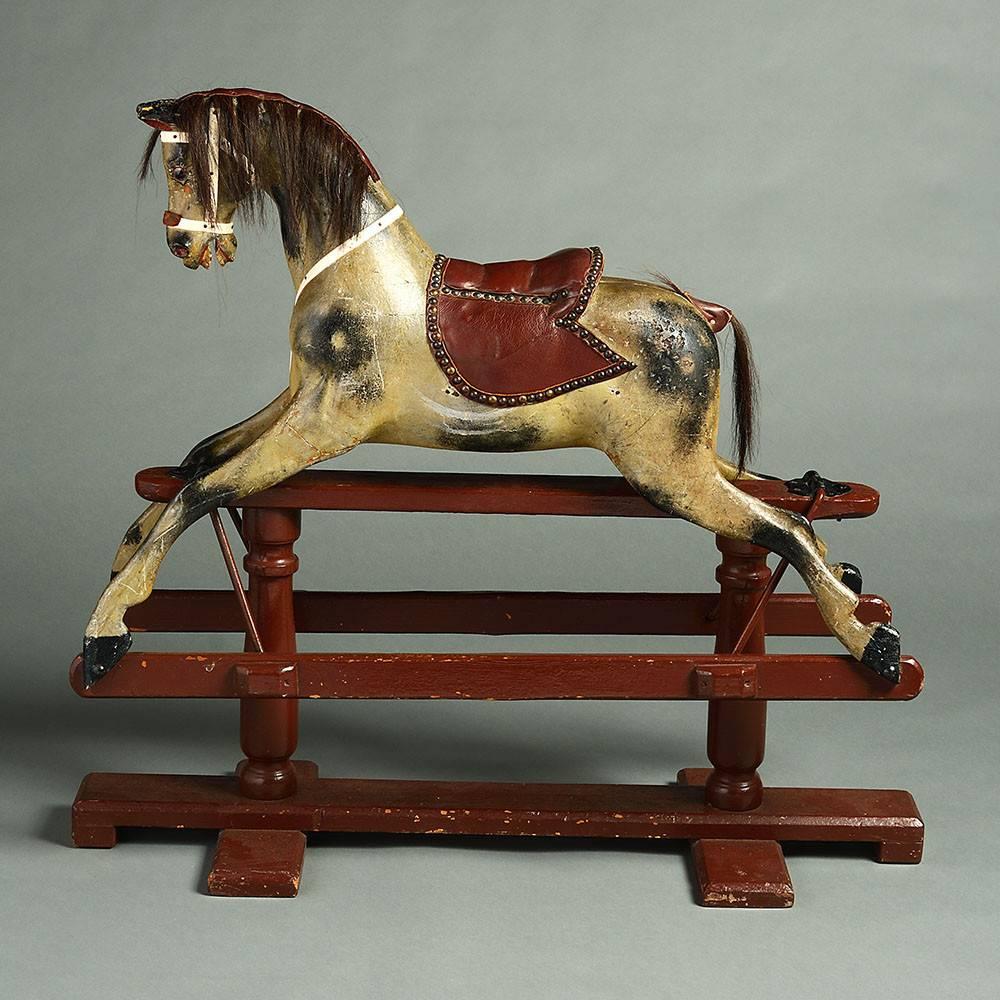 A charming Edwardian Period painted rocking horse, the body realistically modelled, raised on runners and set upon a painted base. 

While historically the toy was reserved for nobility, due to its laborious, elaborate and hence costly