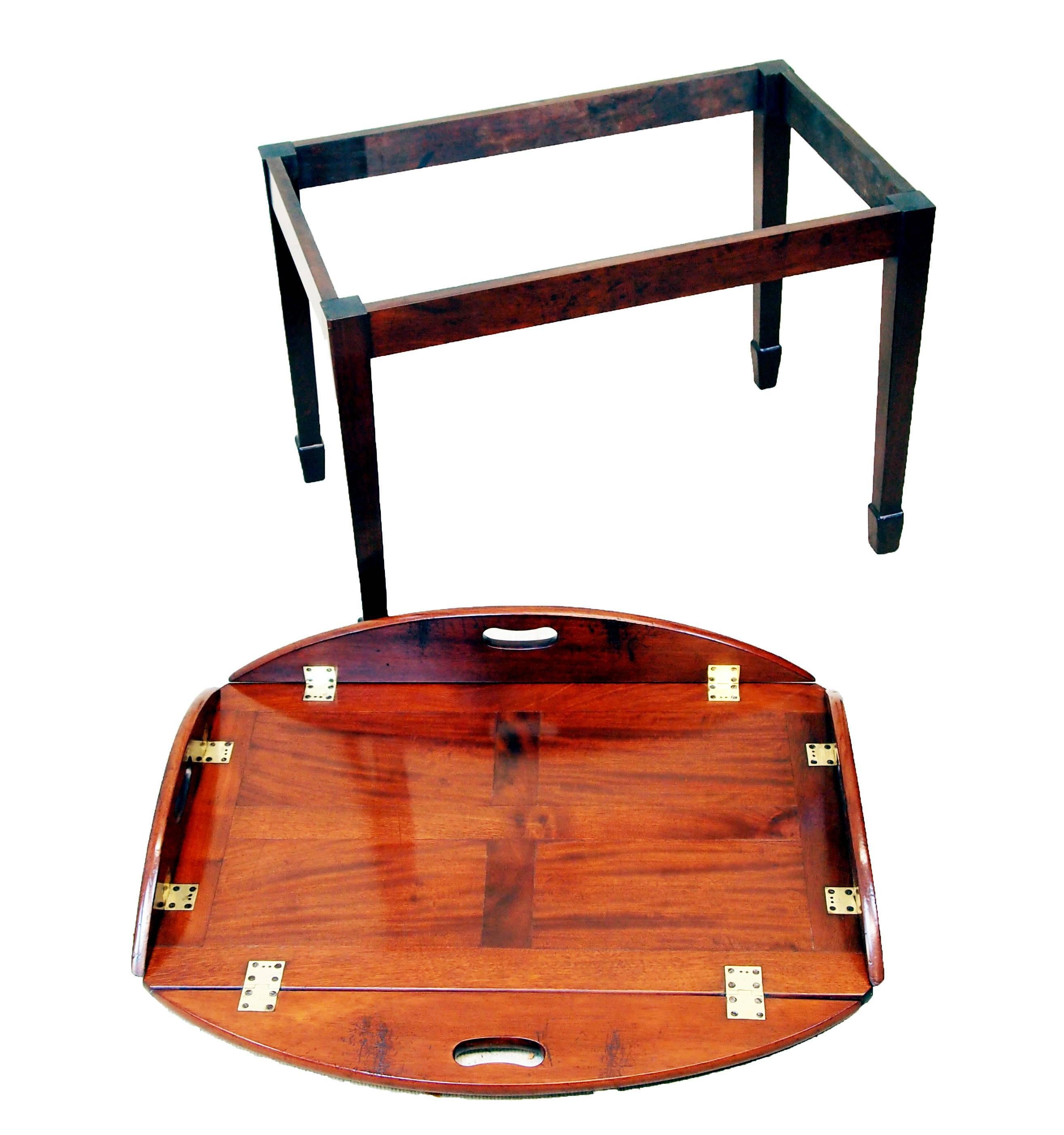 A George III Period Mahogany Oval Butlers Tray Of Panelled 
Construction Having Original Brass Hinges To Folding Sides Housed 
On Later Mahogany Square Leg Stand