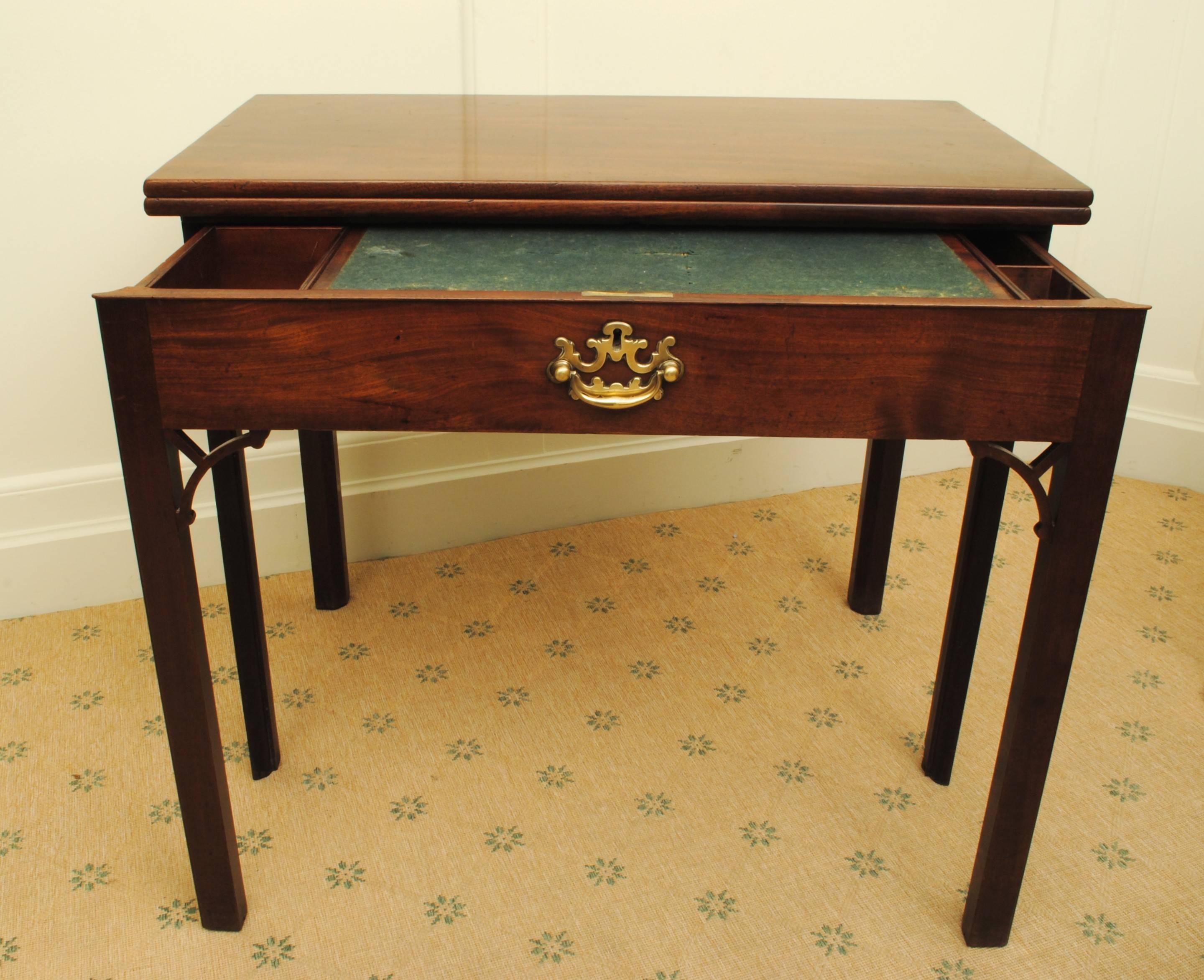 A mid 18th century mahogany table of good colour and patina, the fold over top making a large writing surface and the fitted drawer pulling out with half the front leg for support. Original brass handle.
