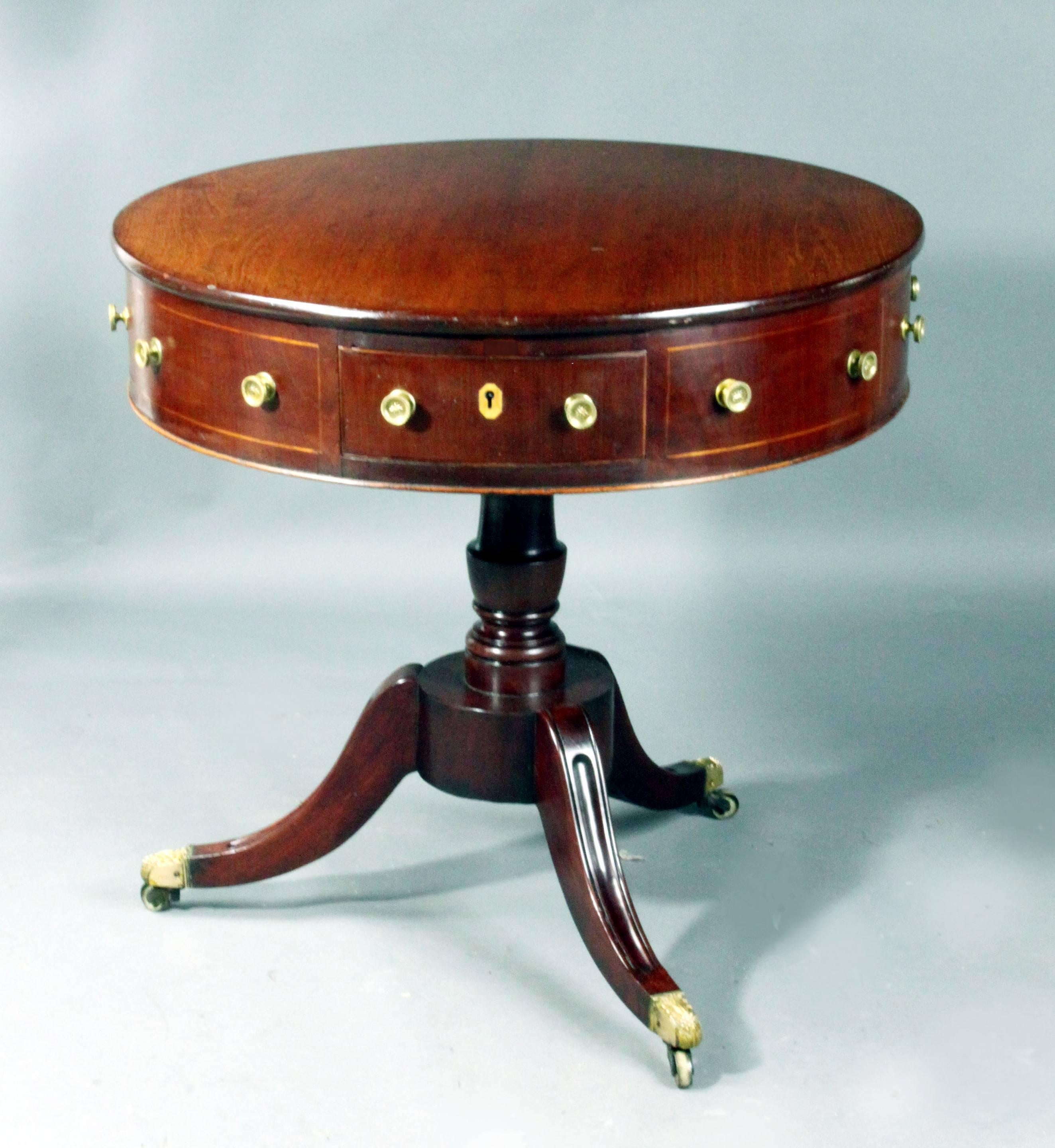 An early 19th century drum table of a good small size: in mahogany with boxwood stringing and boxwood escutcheons, oak lined drawers, 4 real drawers and 4 false, revolving polished top and finely cast casters; all original apart from the knobs 