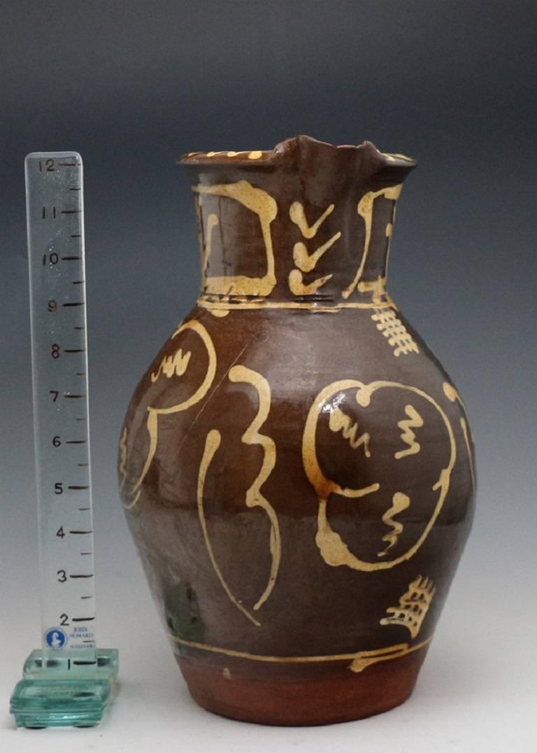 A large sized slipware jug with a cream coloured slip applied to dark brown body. 
The slip work is a provincial and folksy adding to the naive appeal. 
A stunning country piece its large scale providing various decorative opportunities.
