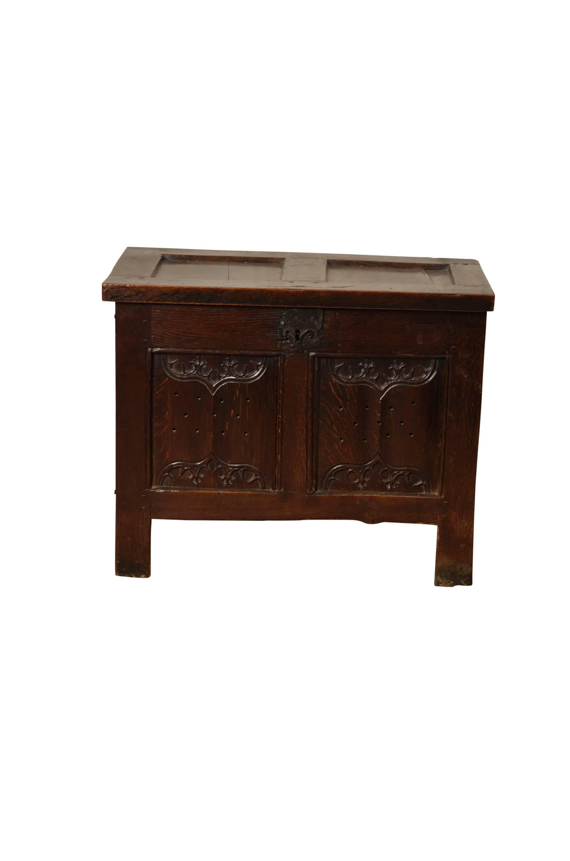 Oak small coffer, the two panelled front with enriched parchemin/linenfold carving drilled with holes for the storage of food, the two panelled top opening to reveal a lidded candlebox and a rare rear narrow shelf. Raised on stile supports.