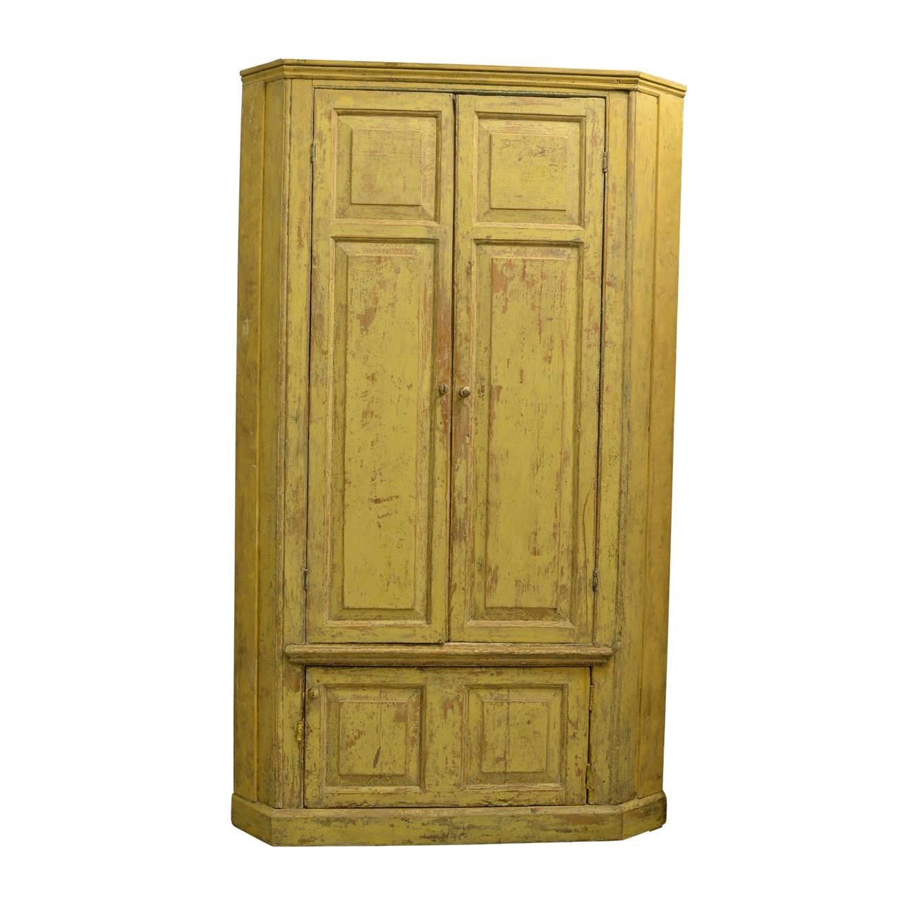 Pine floor standing corner cupboard retaining the original paint finishes, the exterior yellow ochre and the interior blue/turquoise, the upper part with two doors opening to reveal the original shaped, shelves with architectural arched surround,