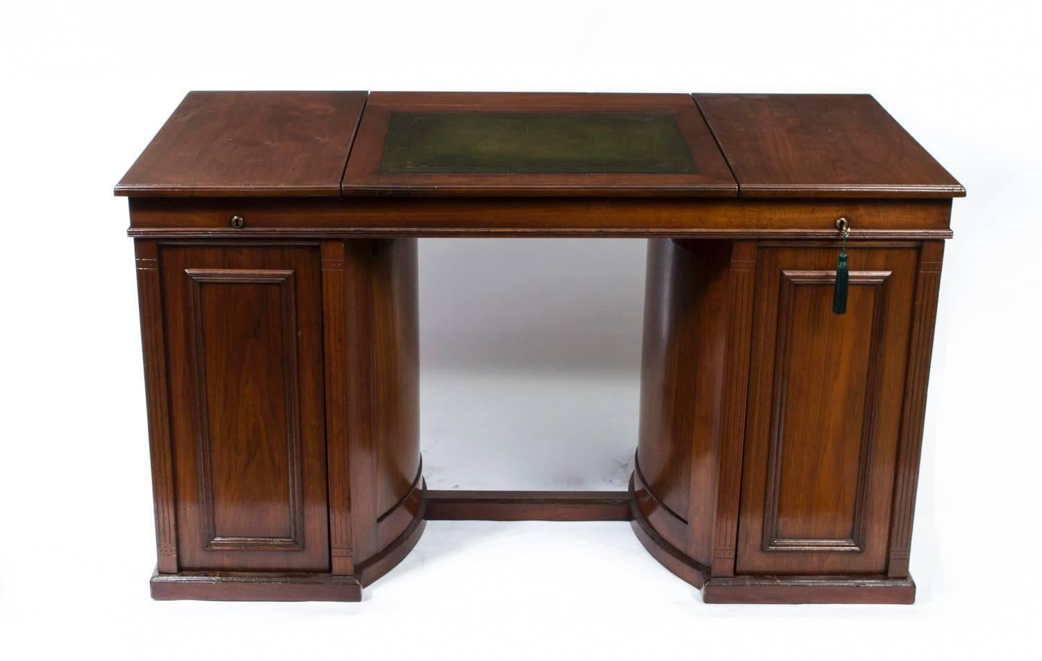his is an exquisite English Antique Victorian flame mahogany pedestal desk, Circa 1870 in date. 

It has a central hinged top inset sage green and gold tooled leather writing surface above a pair of pedestals fitted with Wooton style swivel action