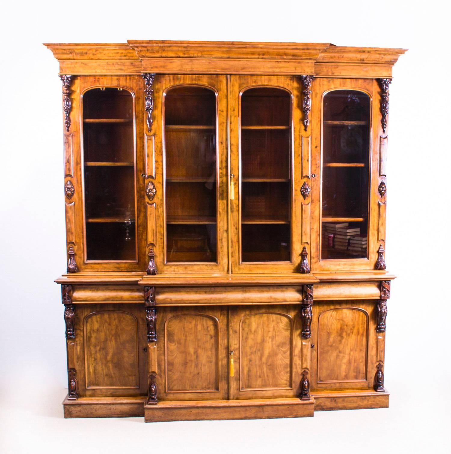 This is a beautiful antique, Victorian Cuban mahogany breakfront library bookcase, masterfully crafted in rich flame mahogany, circa 1860 in date. 

This impressive bookcase features multiple mahogany corbels, panelled doors on the lower cupboards